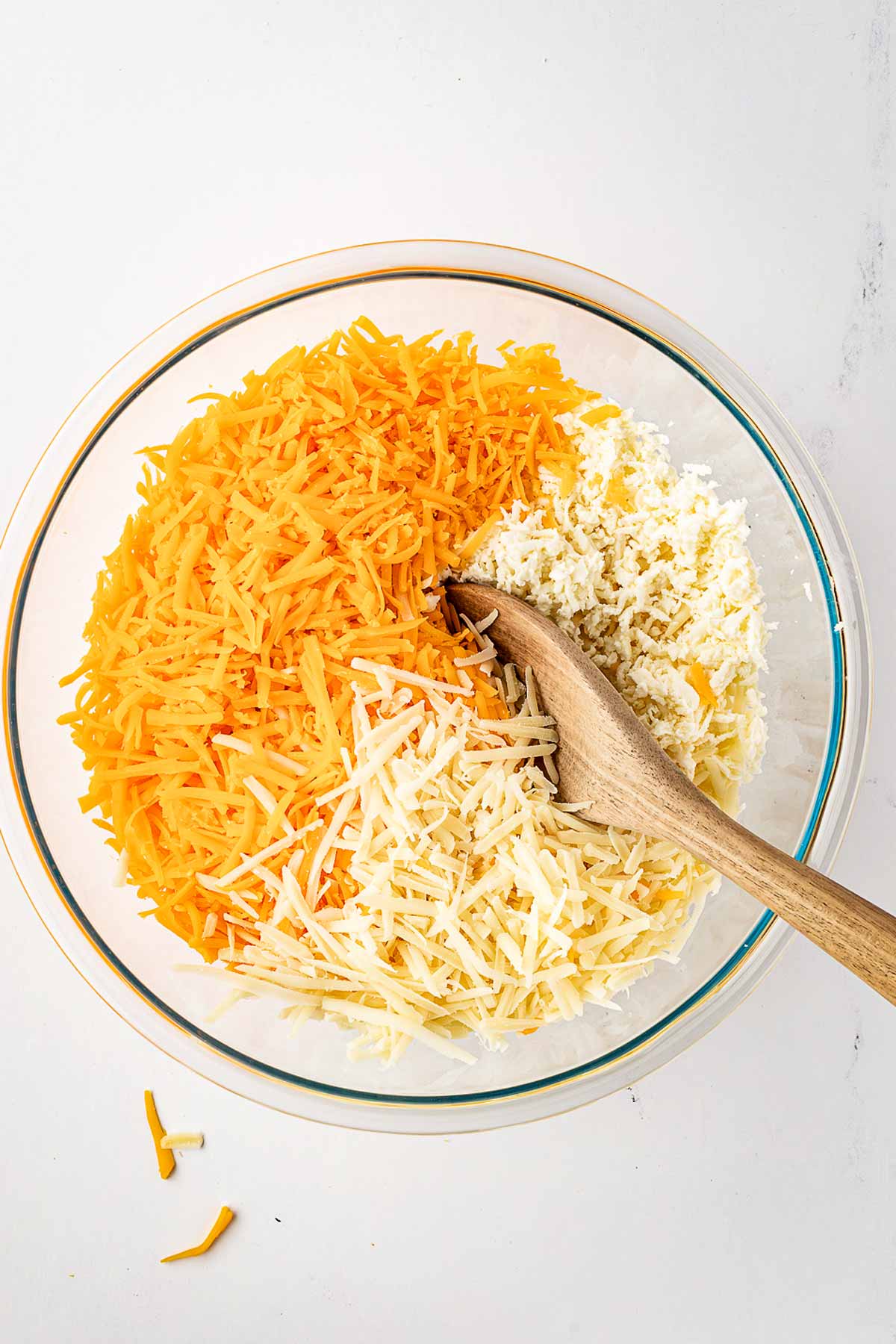 overhead view of shredded cheeses in glass bowl