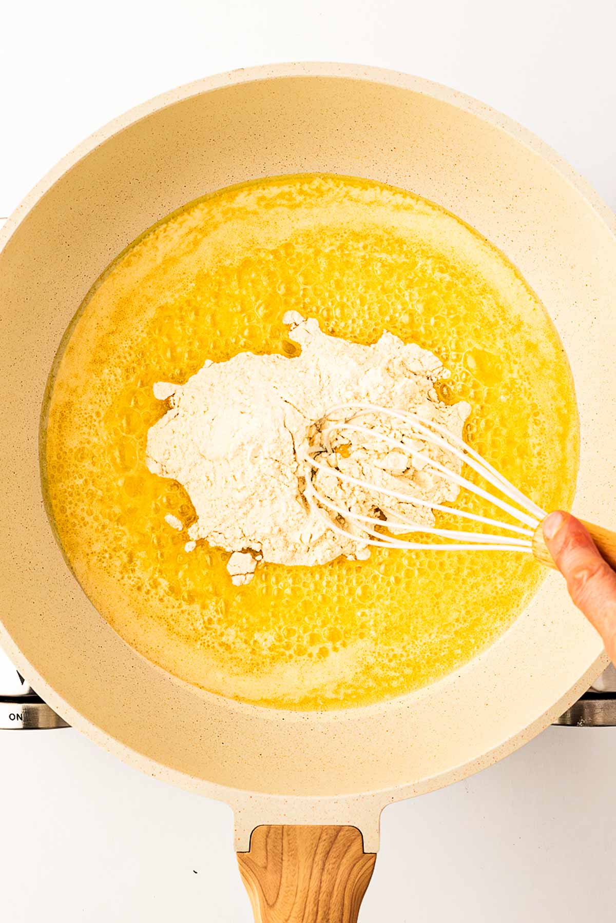 overhead view of flour and melted butter in skillet with whisk