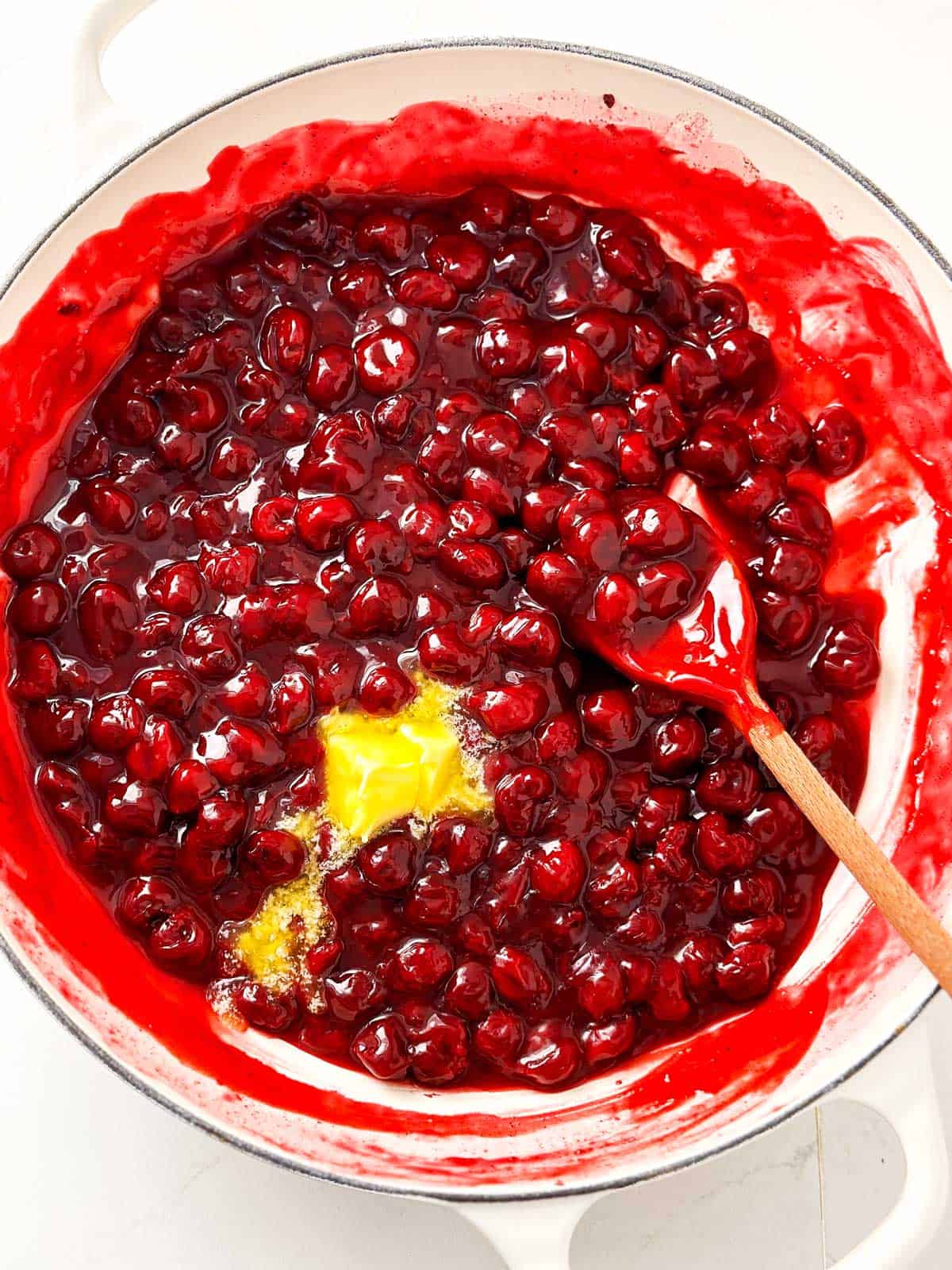 overhead view of cherry pie filling with melting butter in white pan