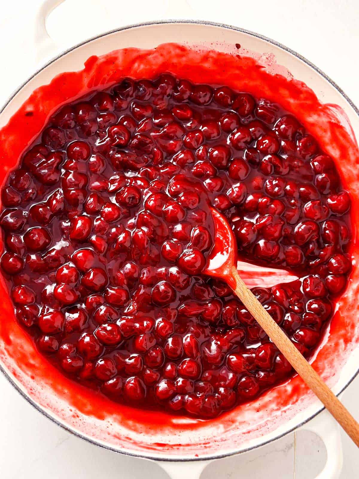 overhead view of cooked cherries in thickened juices in white pan