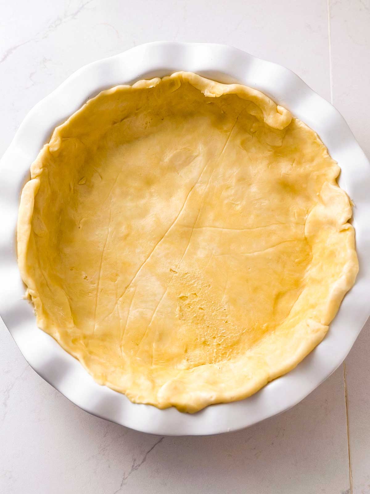 overhead view of pie crust in white pie dish