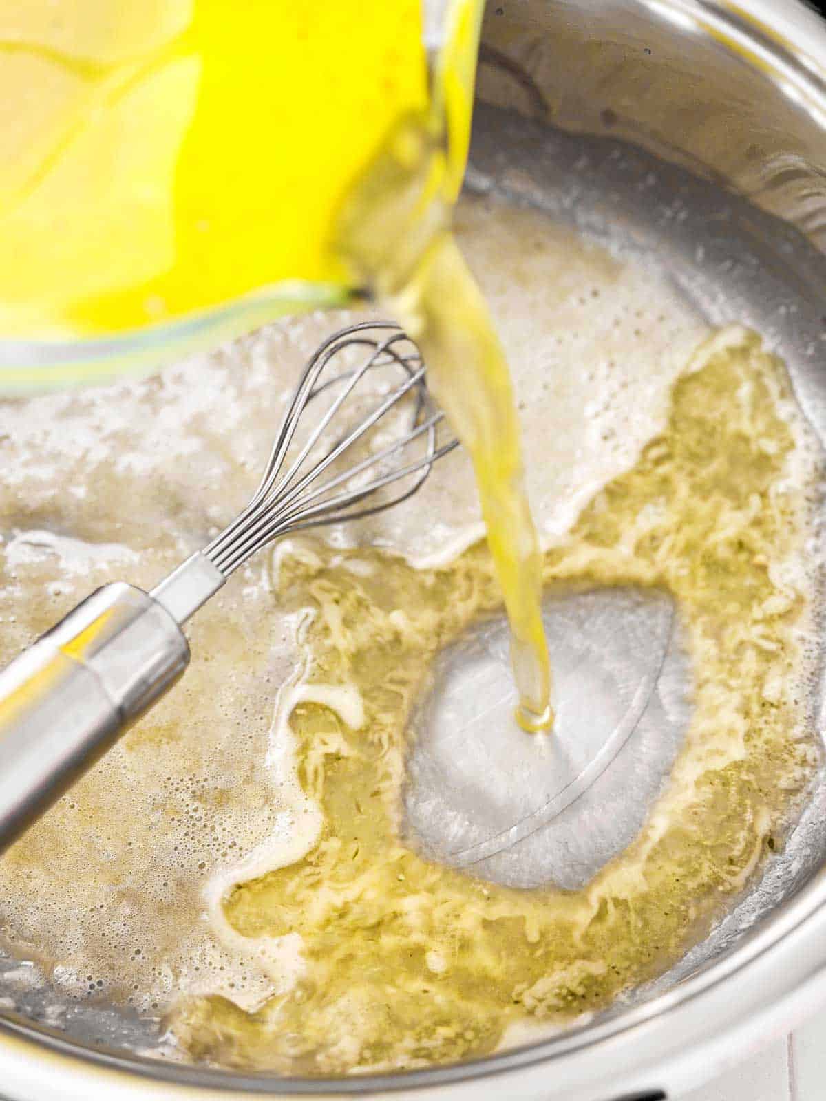 chicken broth pouring into skillet