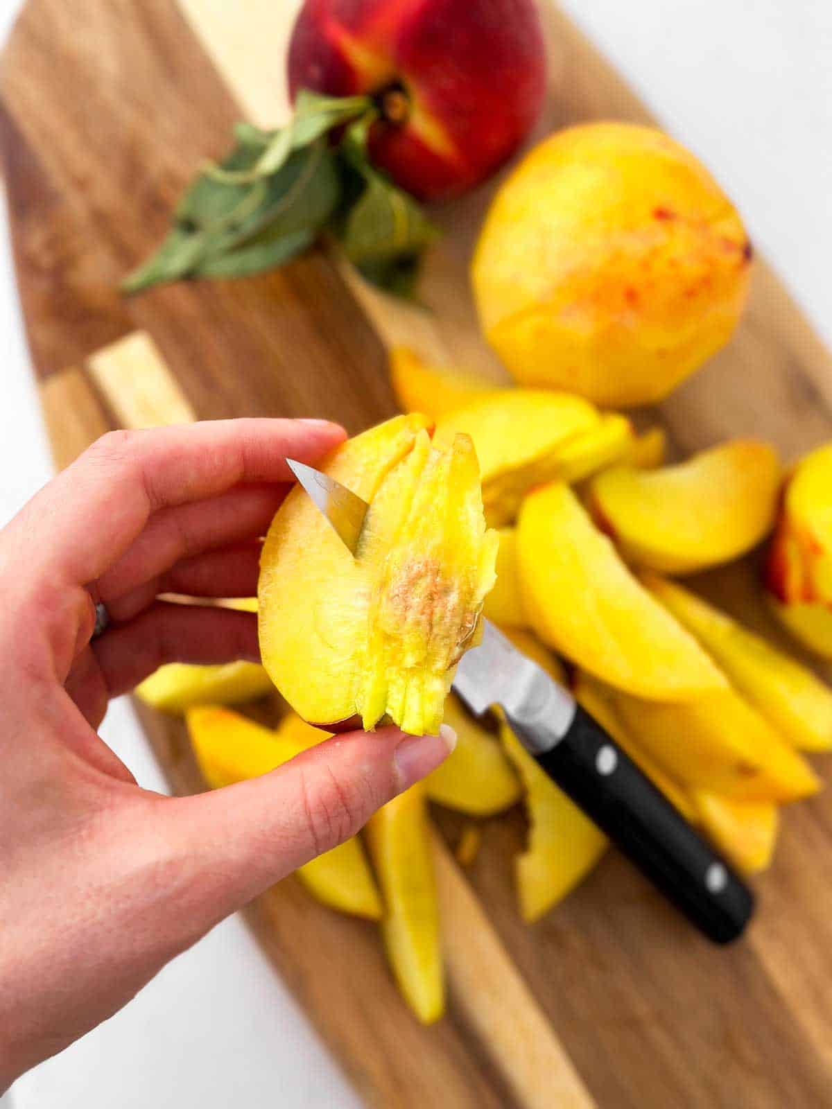 female hands removing pit from peach