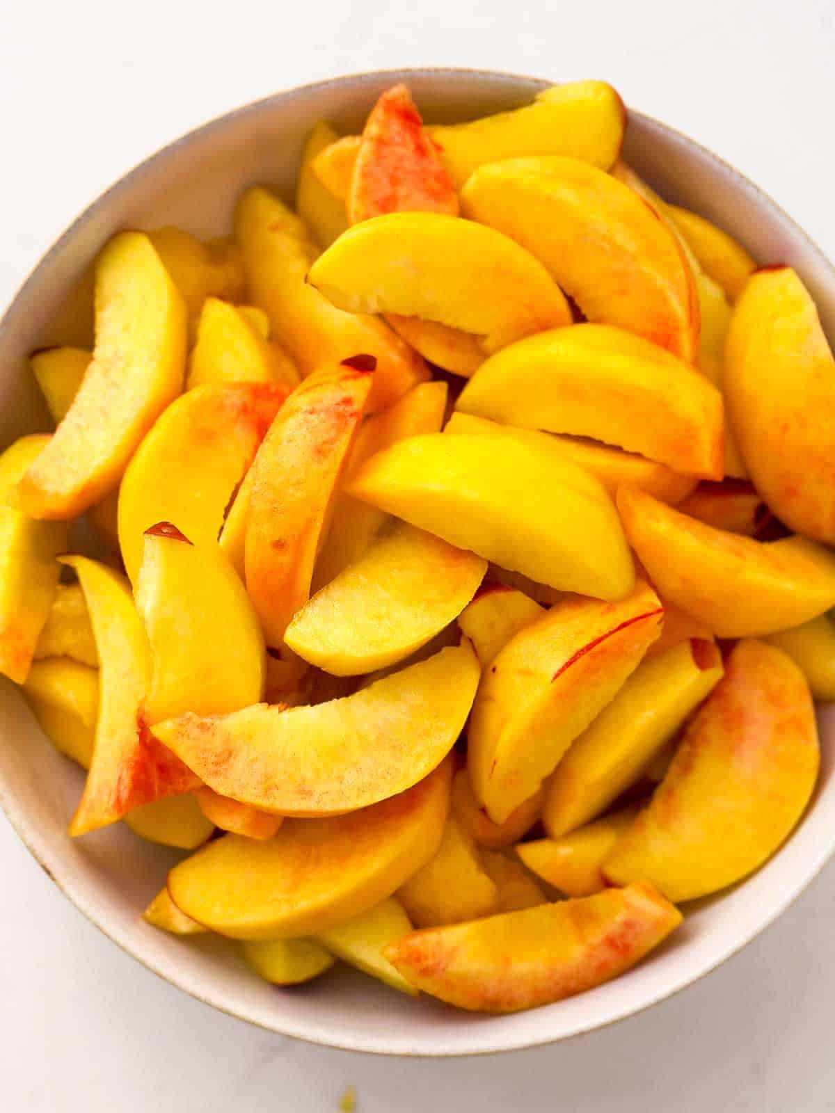 overhead view of white bowl filled with peach slices