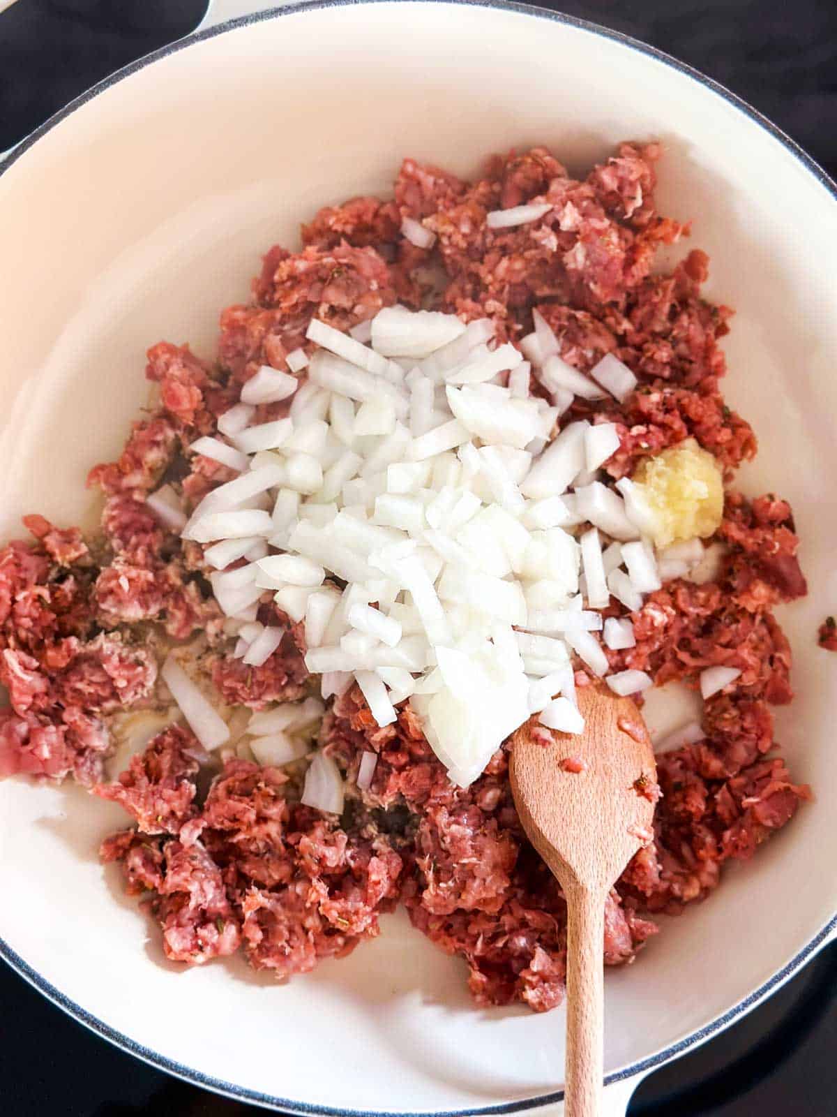 overhead view of raw Italian sausage and onion in skillet