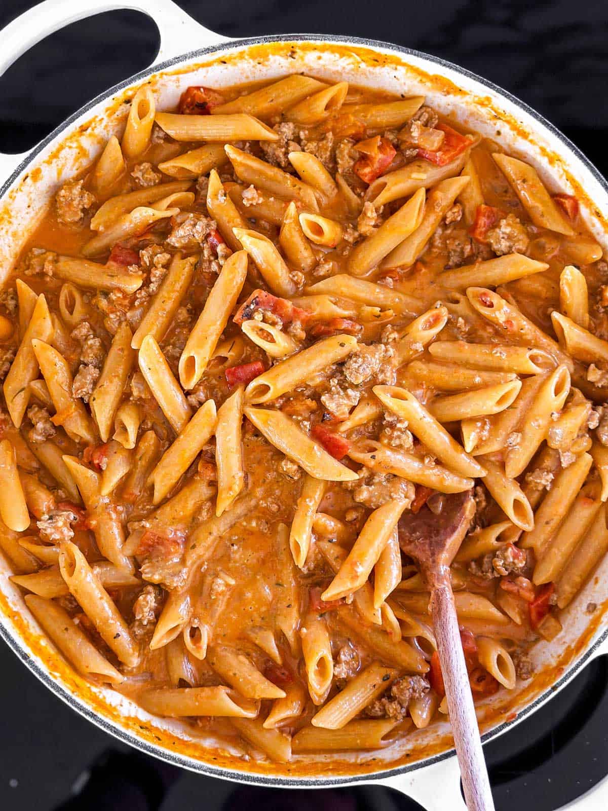 overhead view of cooked sausage and peppers pasta in skillet