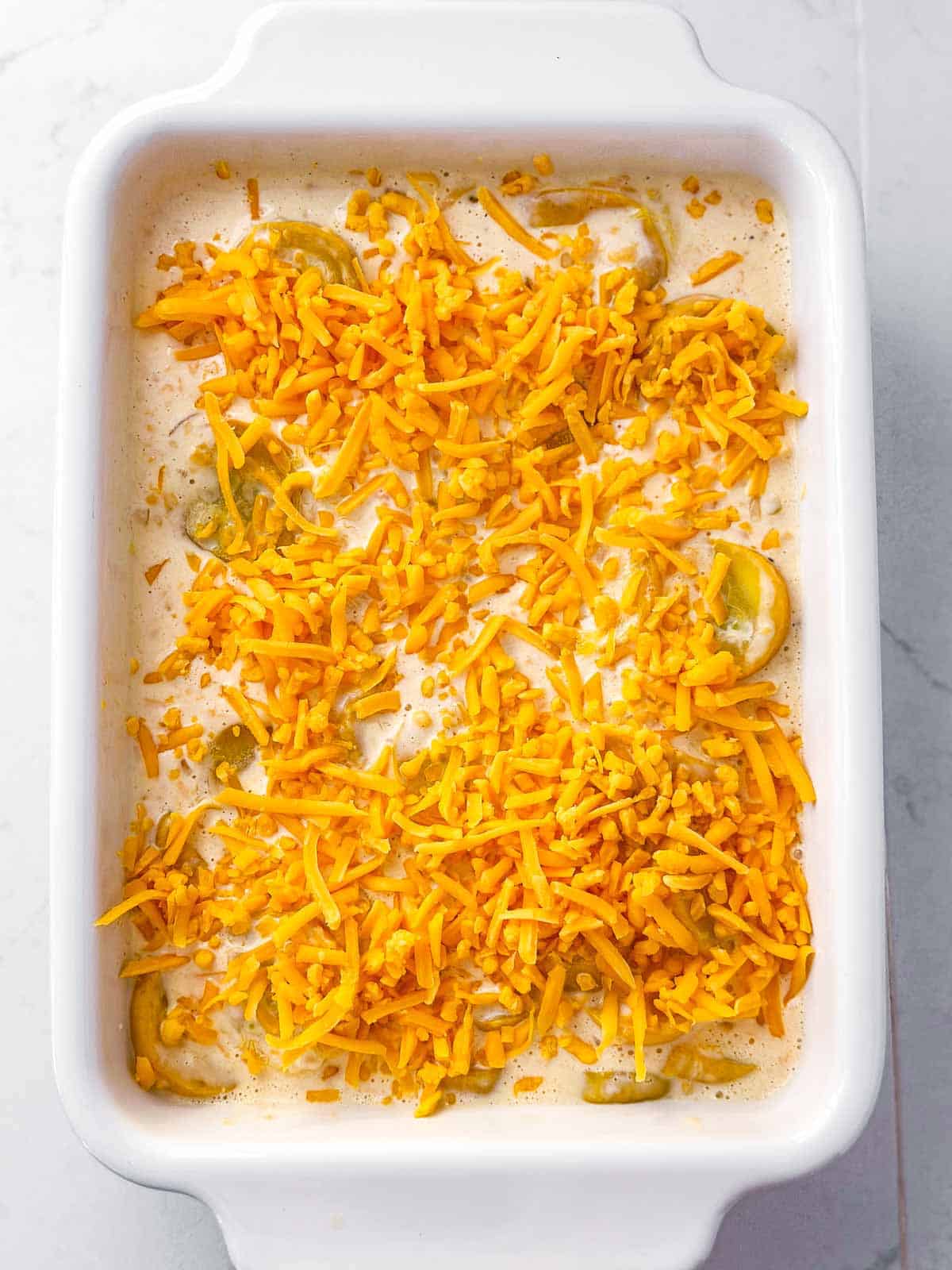 overhead view of unbaked casserole topped with shredded cheddar cheese