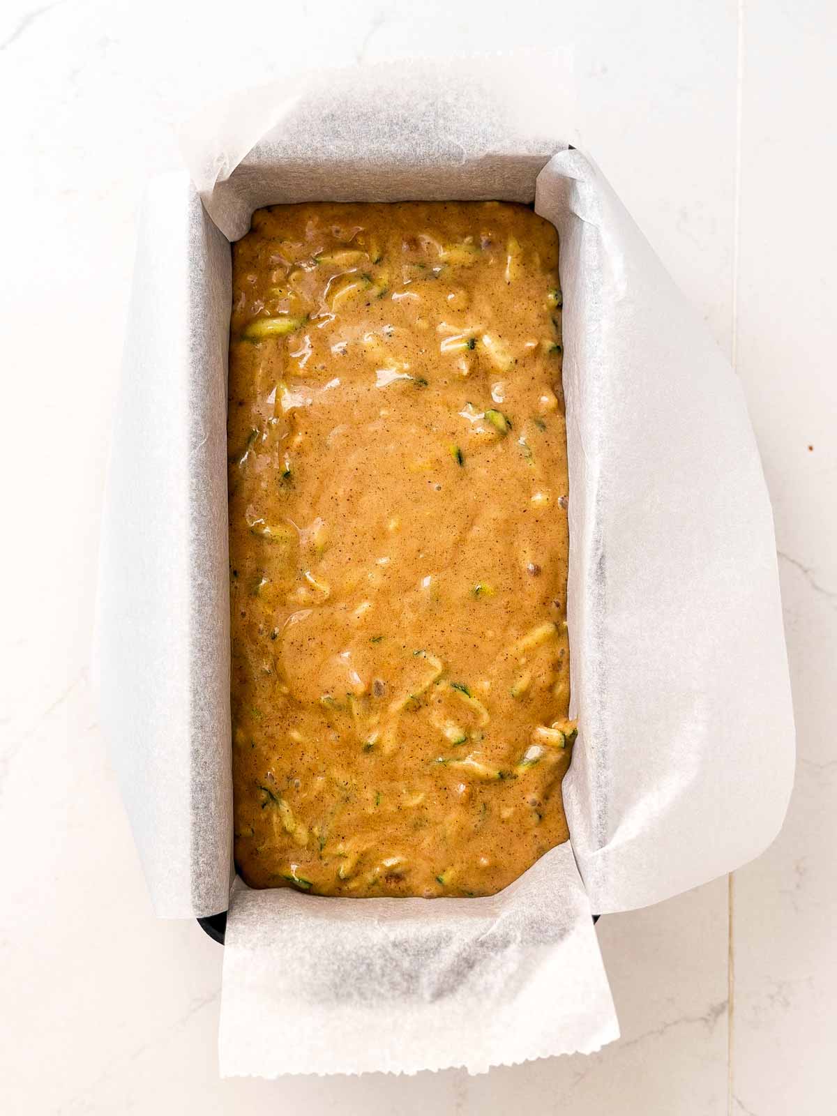 overhead view of zucchini bread batter in lined loaf pan