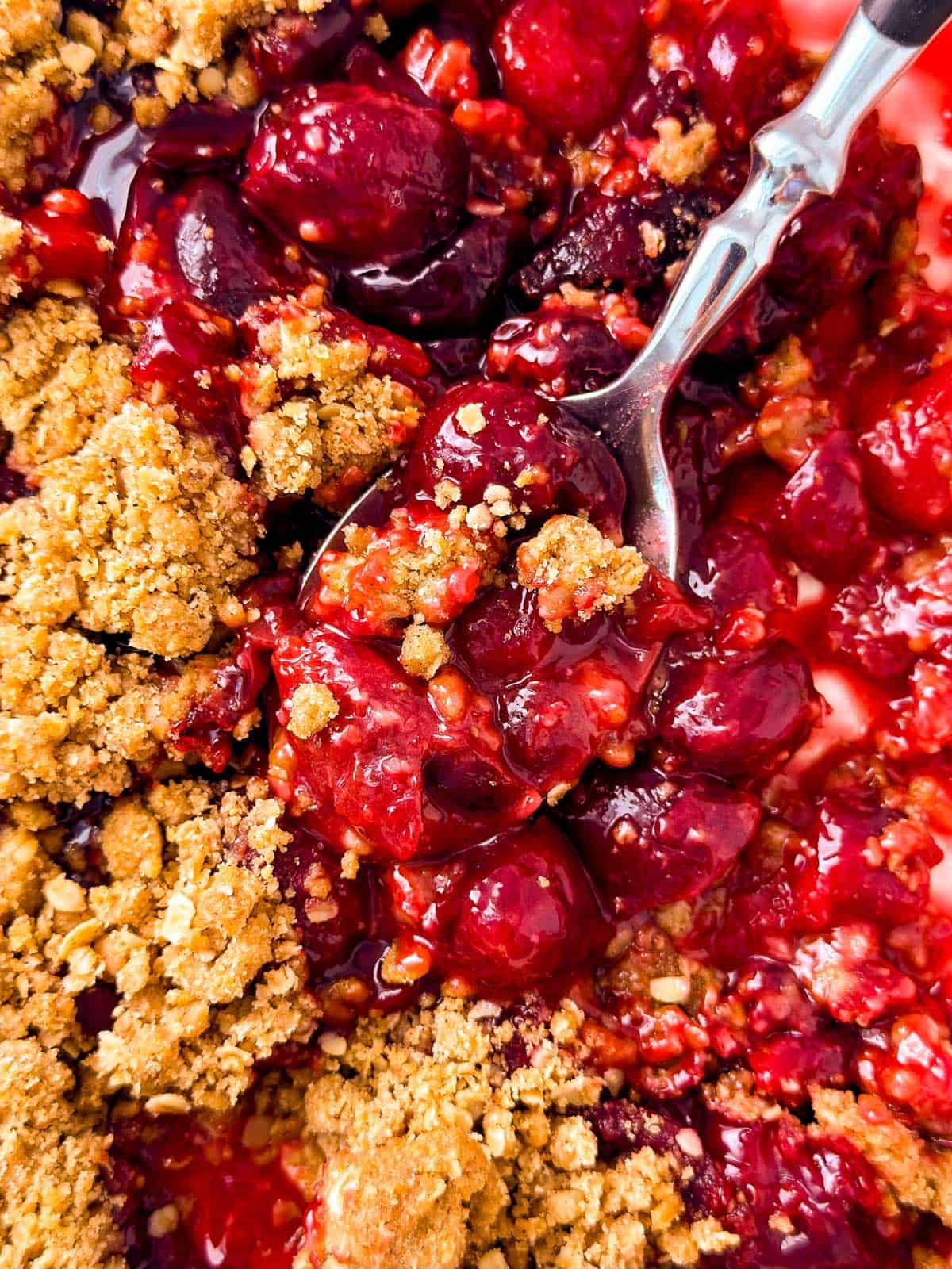 overhead close up view of spoons stuck in cherry crisp