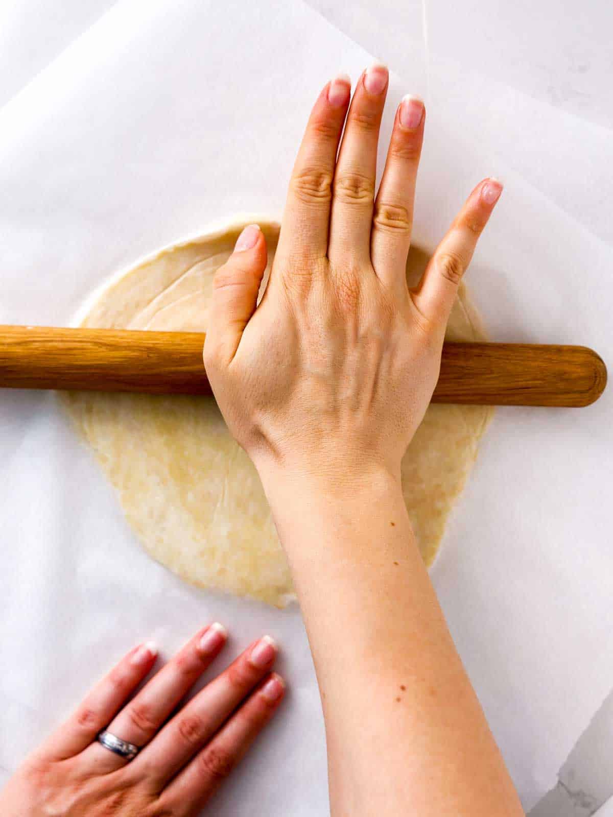 overhead view of female hands rolling out pie crust