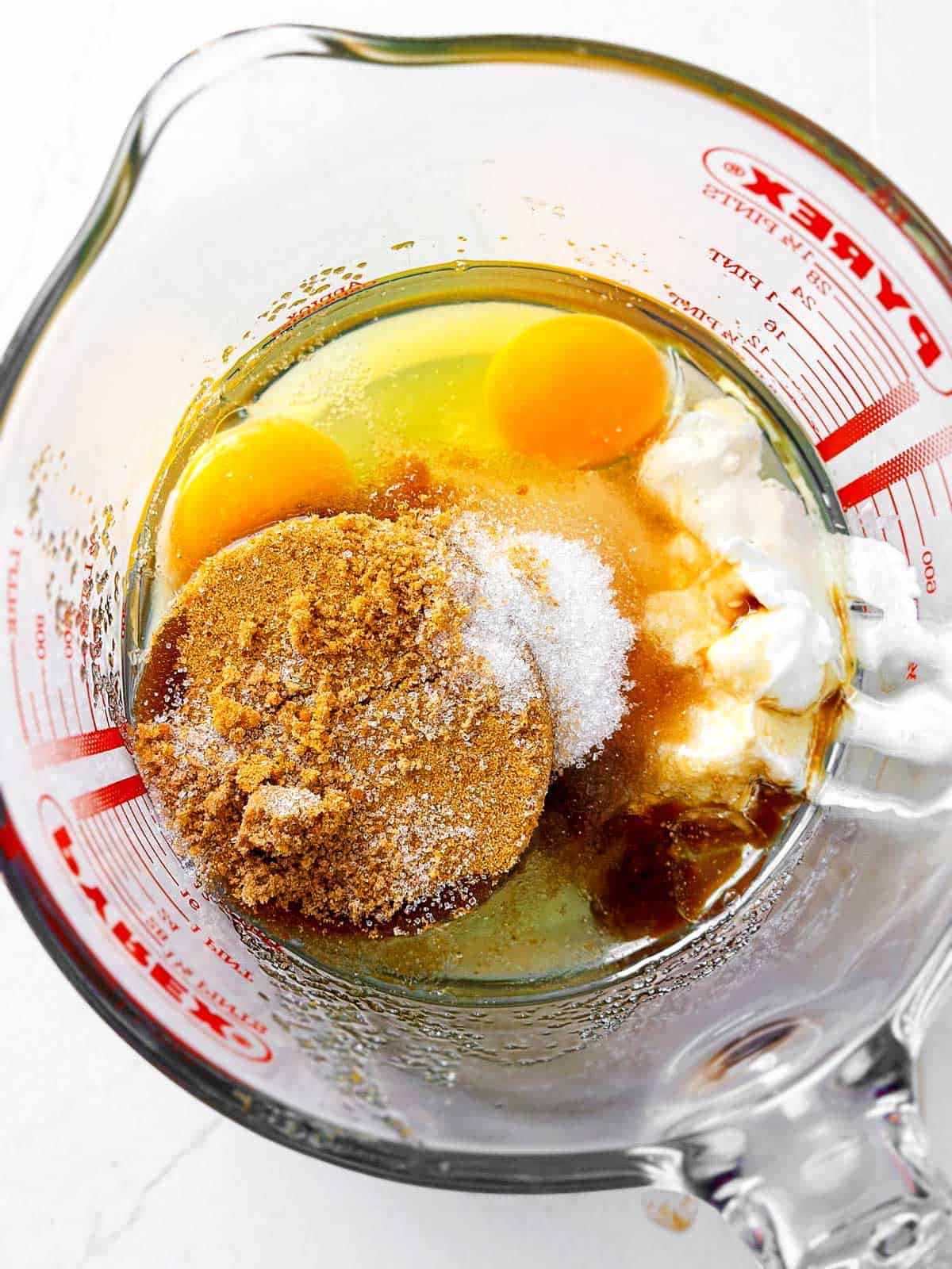 overhead view of uncombined wet ingredients for chocolate zucchini bread in glass measuring jug