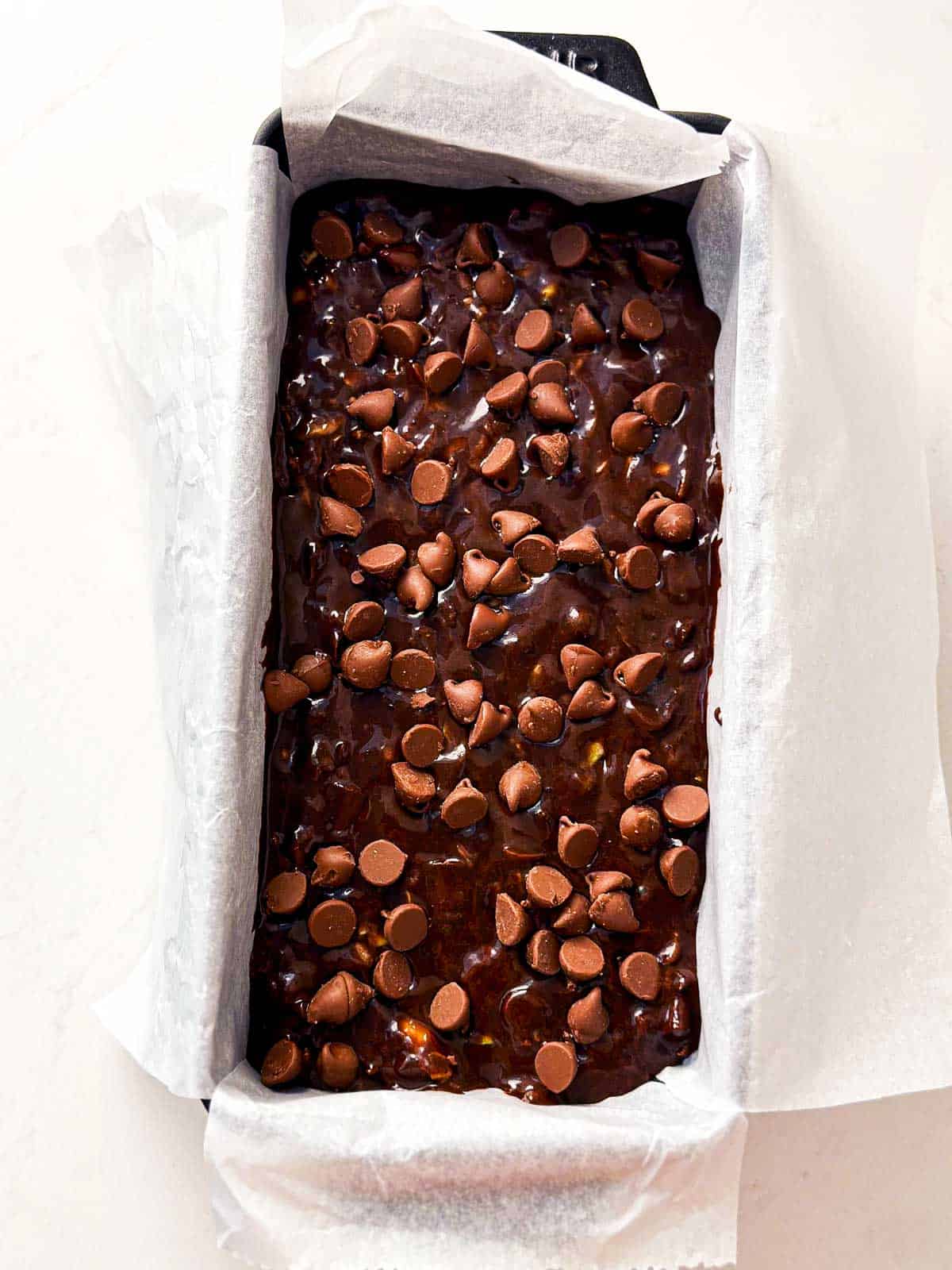 overhead view of batter for chocolate zucchini bread in lined loaf pan