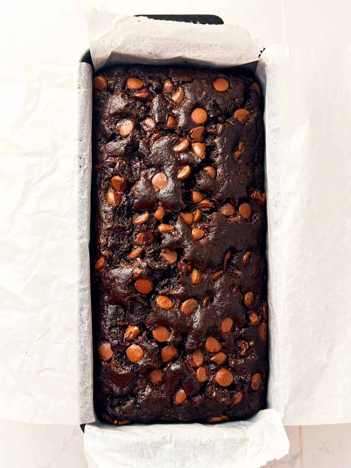 overhead view of baked chocolate zucchini bread in lined loaf pan