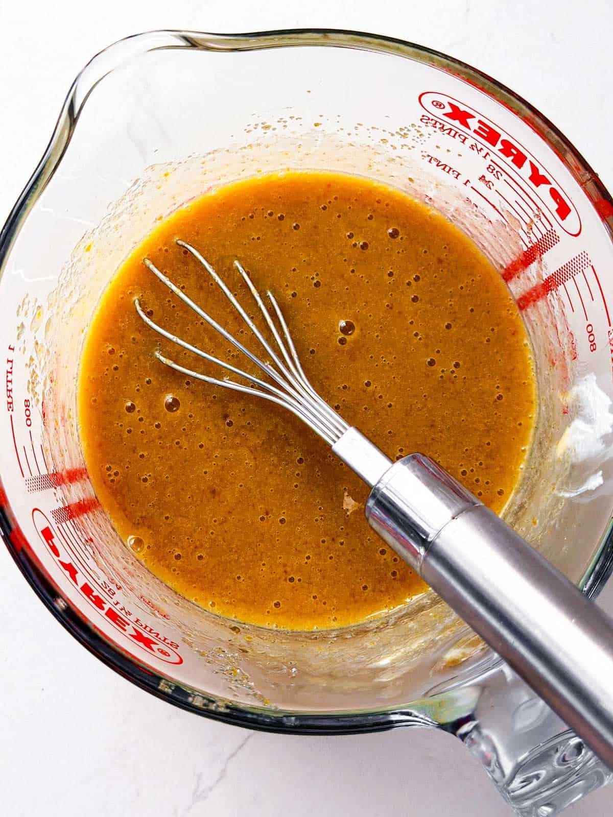 overhead view of combined wet ingredients for chocolate zucchini bread in glass measuring jug