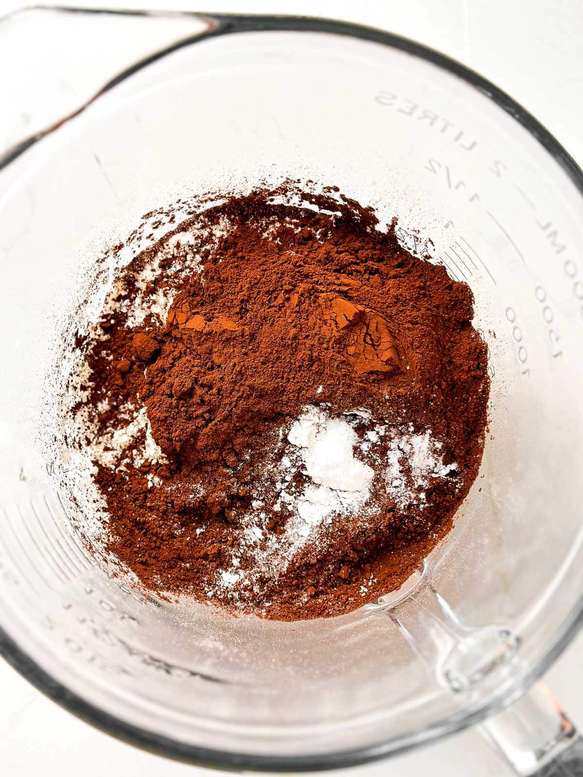 overhead view of uncombined dry ingredients for chocolate zucchini bread in glass mixing bowl