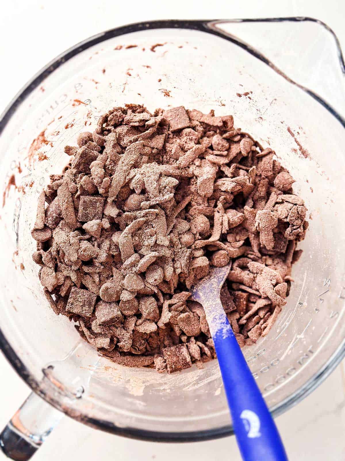 chocolate chips and chocolate chunks stirred into dry ingredients for chocolate zucchini bread in glass bowl