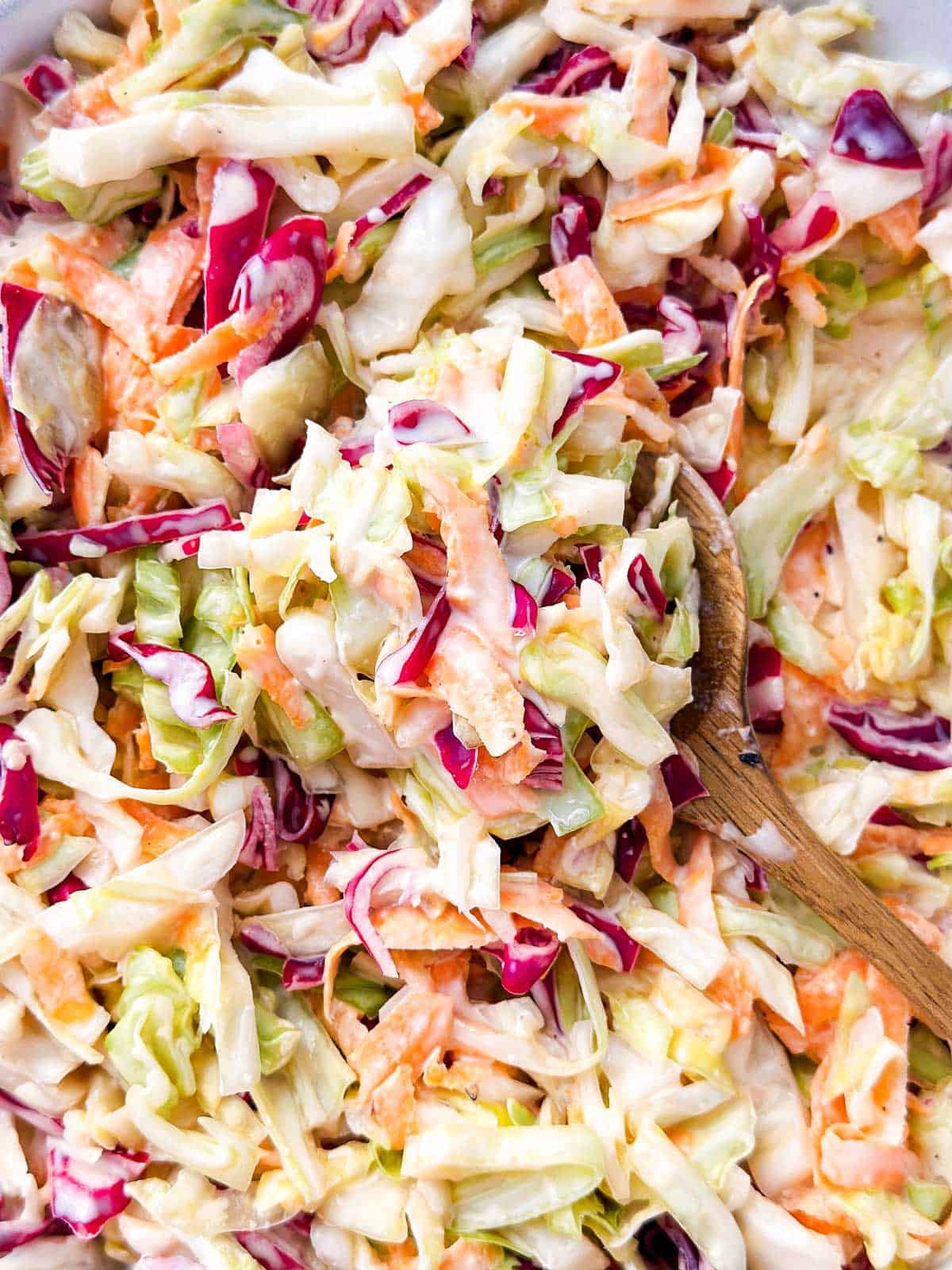 overhead close up view of wooden spoon filled with coleslaw