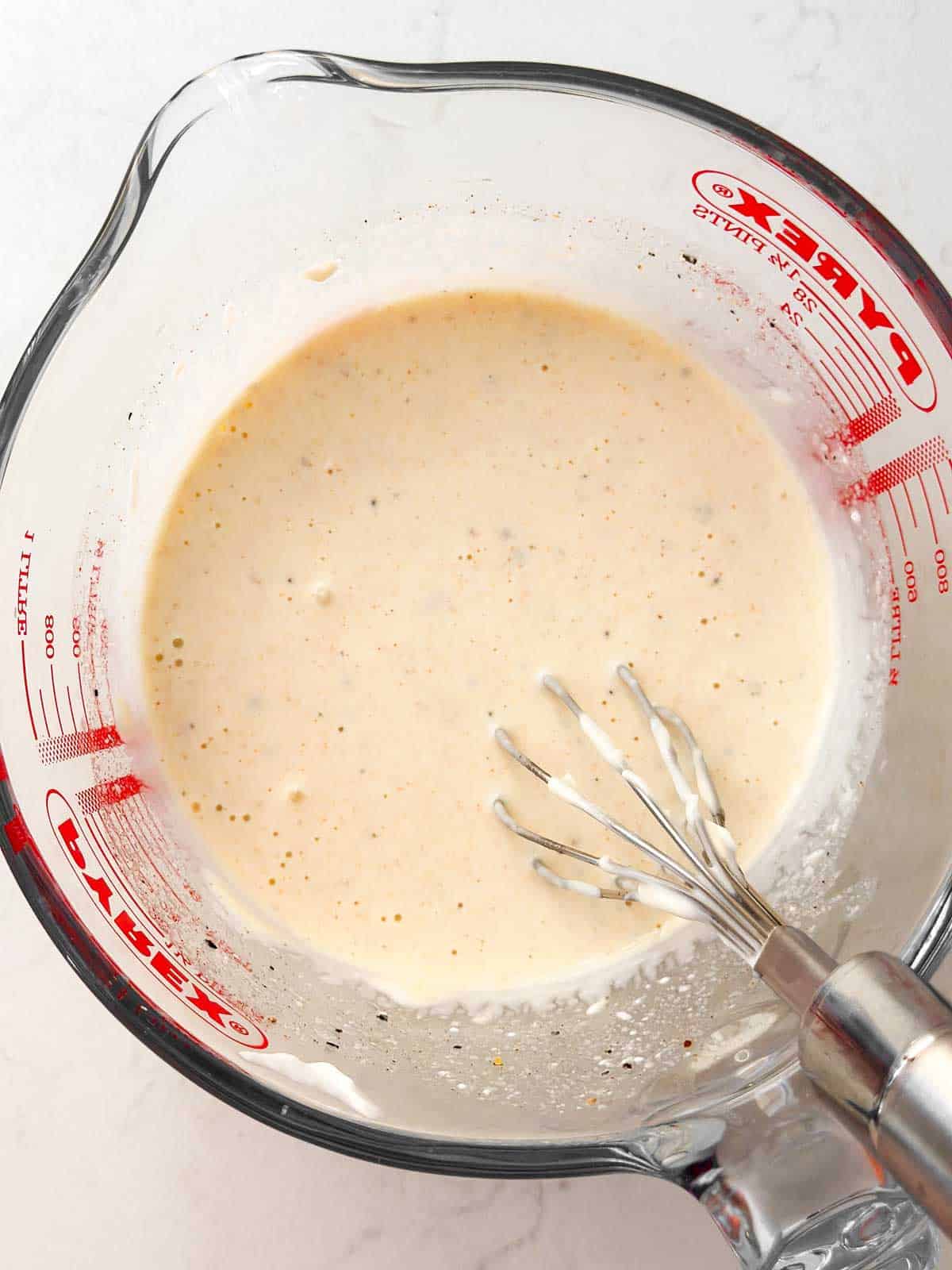 overhead view of coleslaw dressing in glass measuring cup