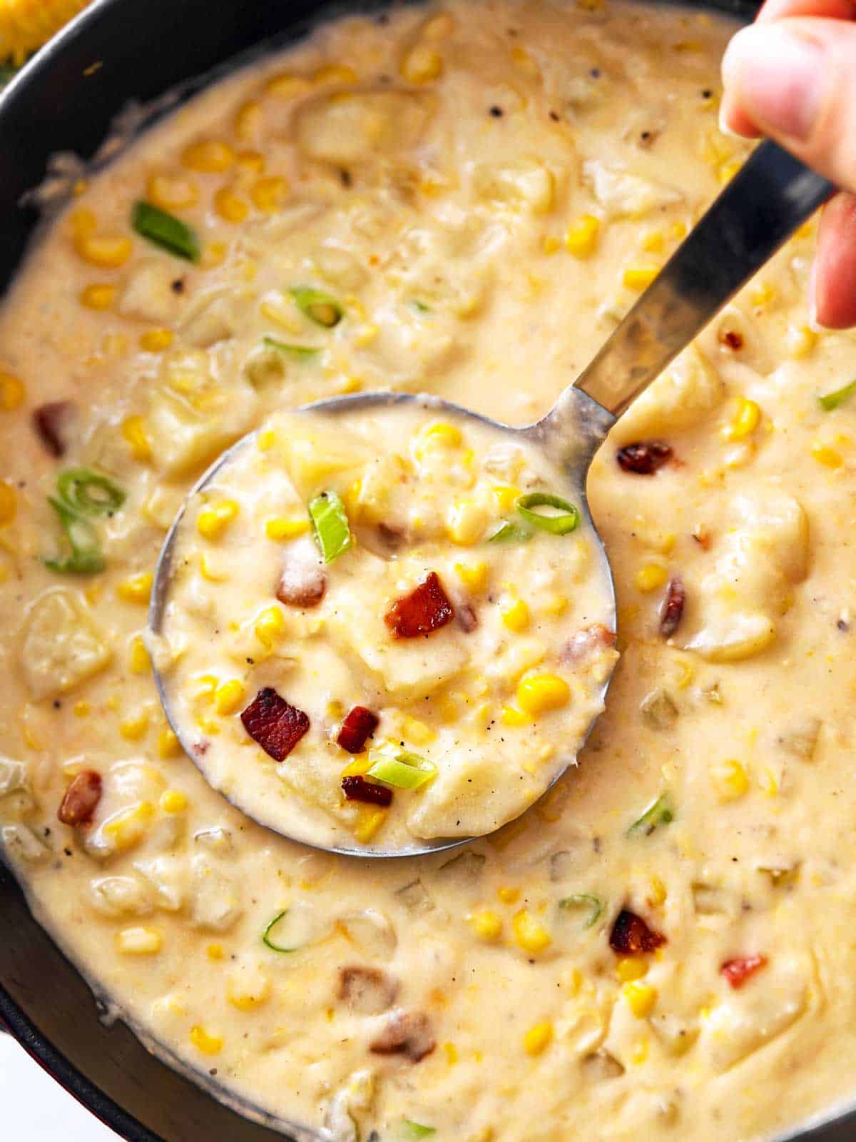 overhead close up view of ladle scooping corn chowder from Dutch oven