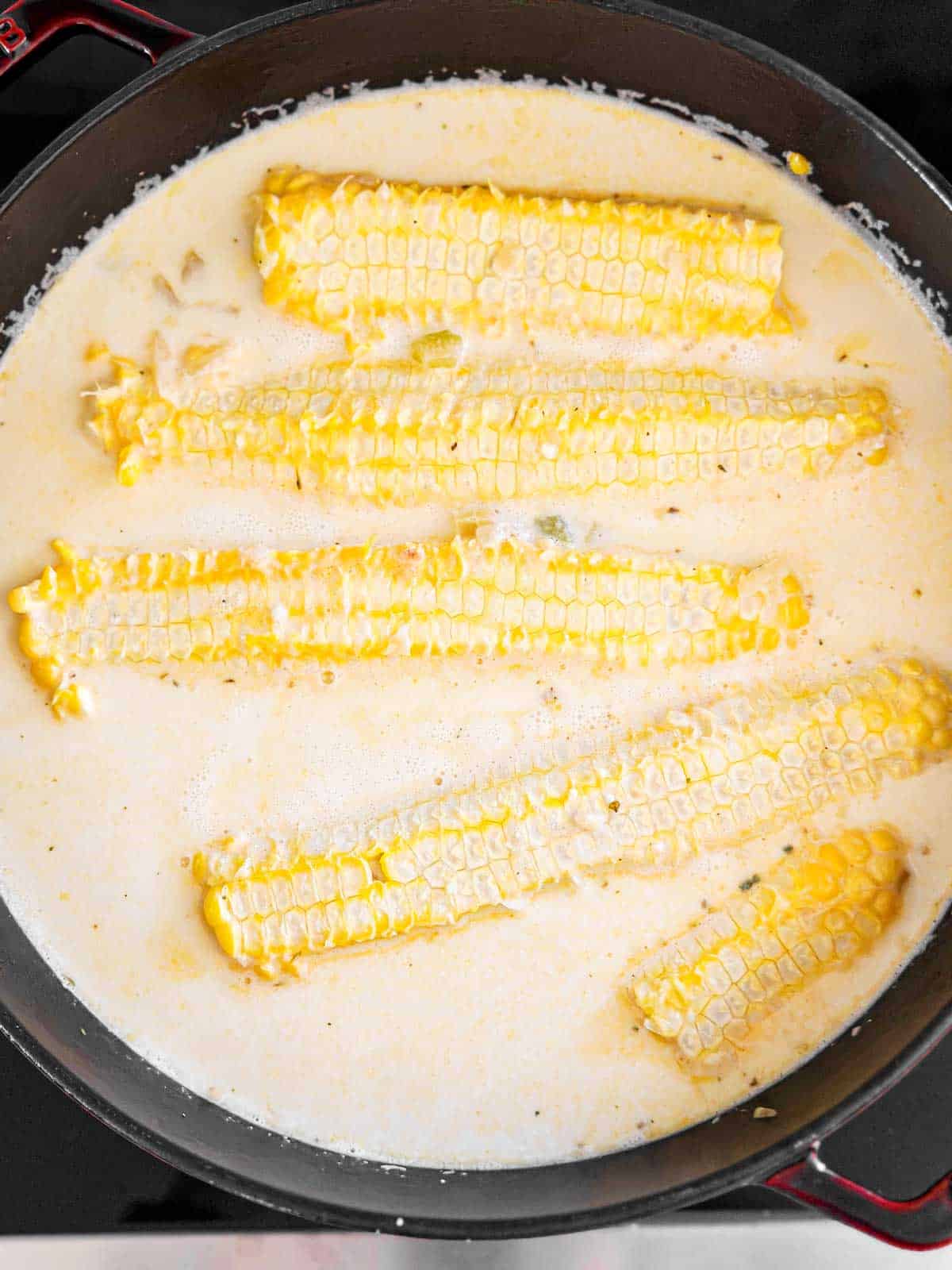 overhead view of four empty corn cobs in uncooked corn chowder