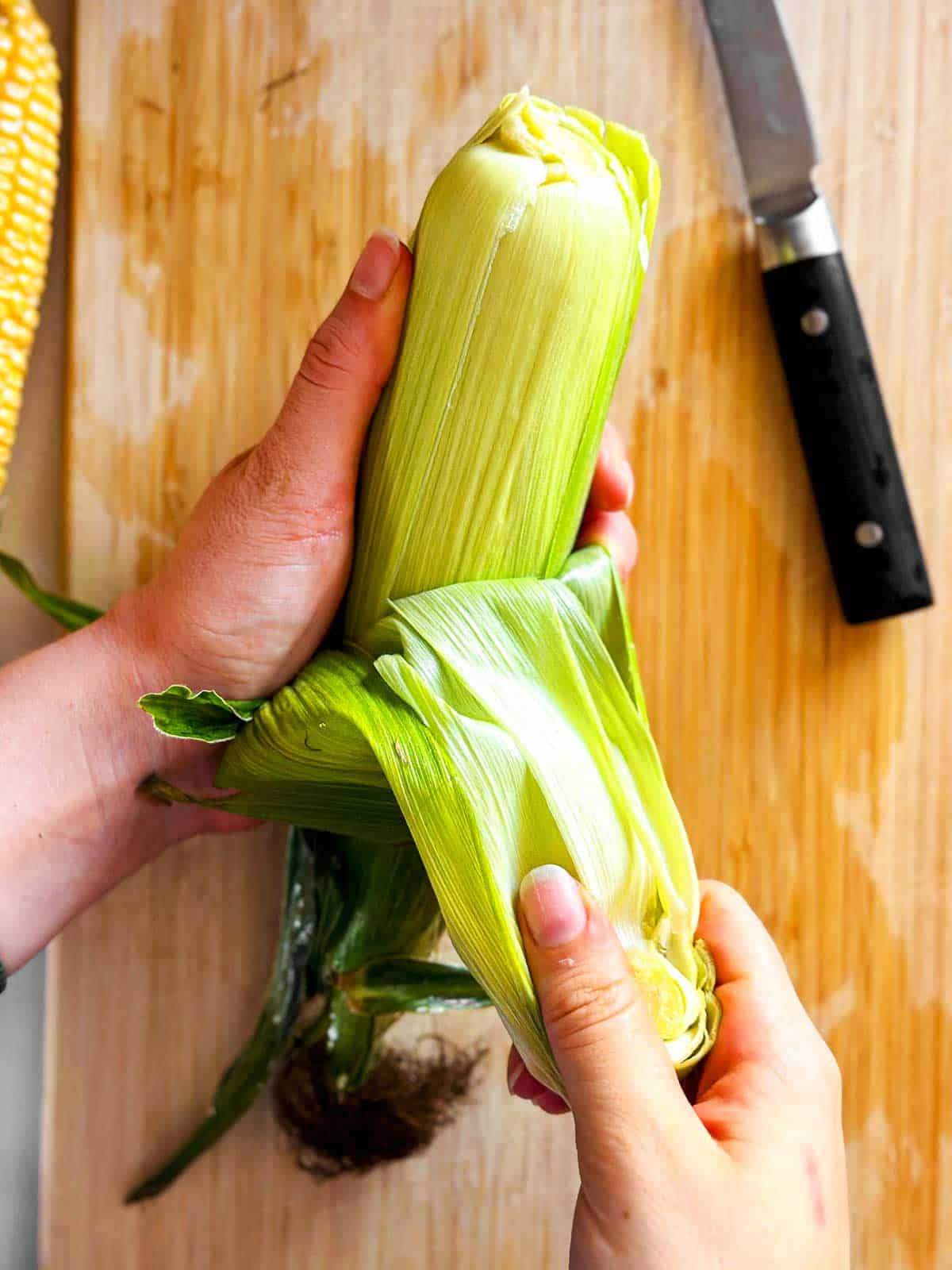 female hands removing husk from corn