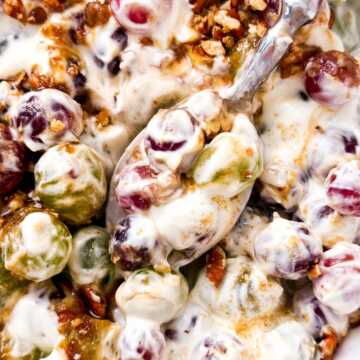 overhead close up view of spoon scooping creamy grape salad