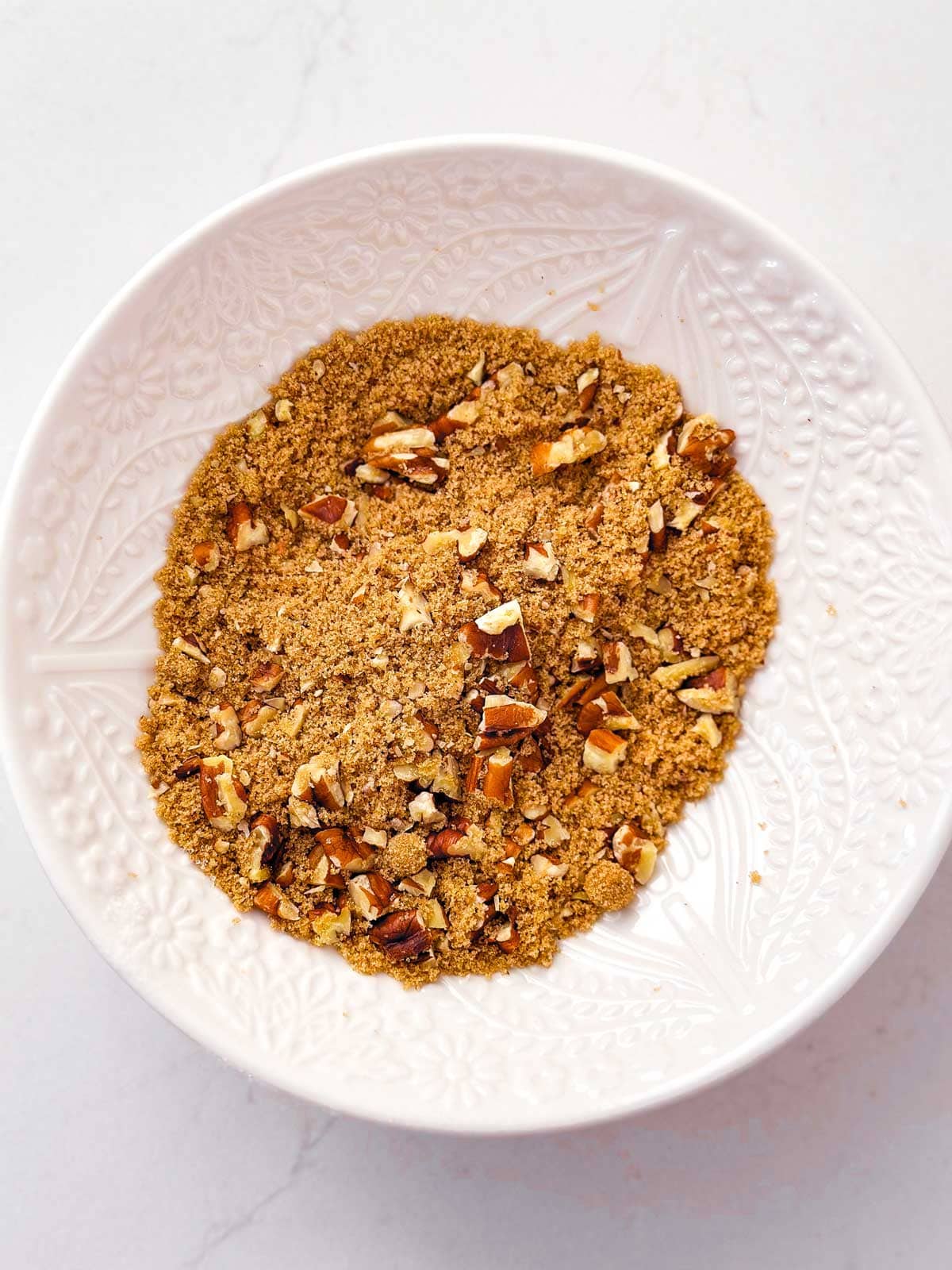 overhead view of brown sugar and chopped pecans in small white bowl