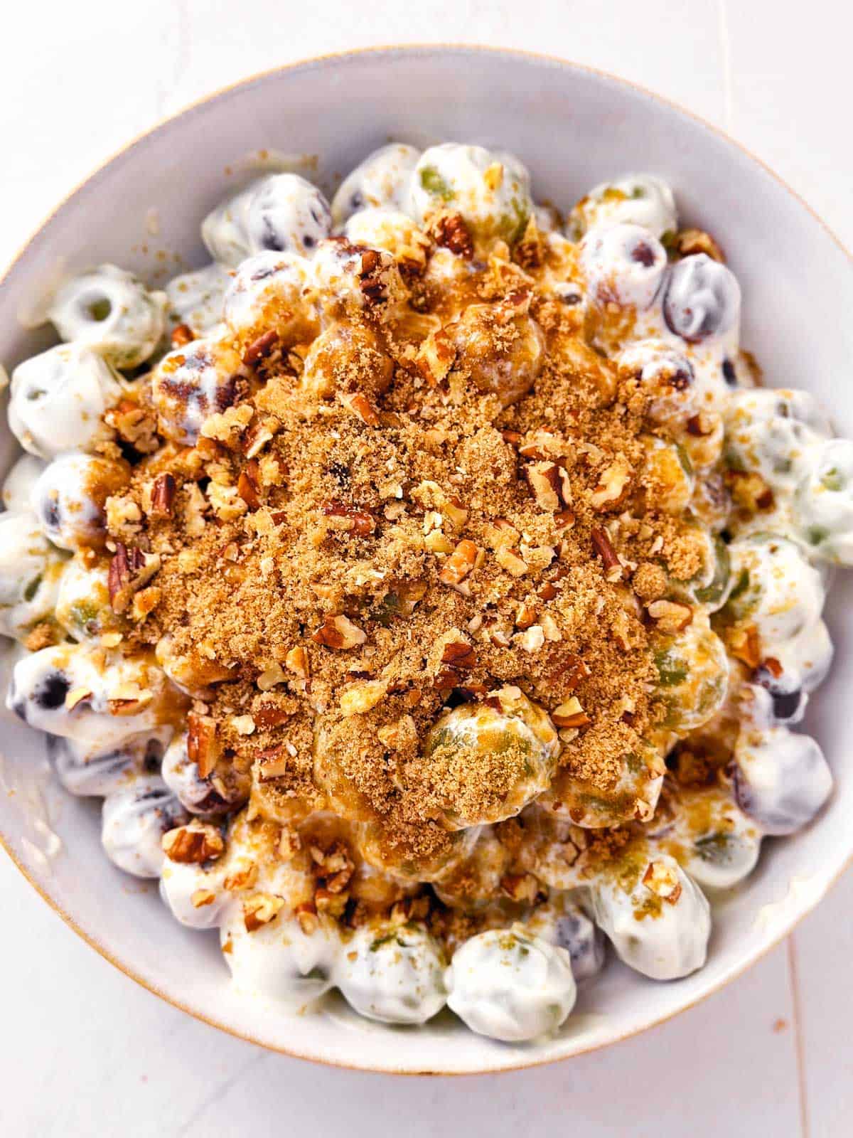 overhead view of prepared grape salad with brown sugar pecan topping in white bowl