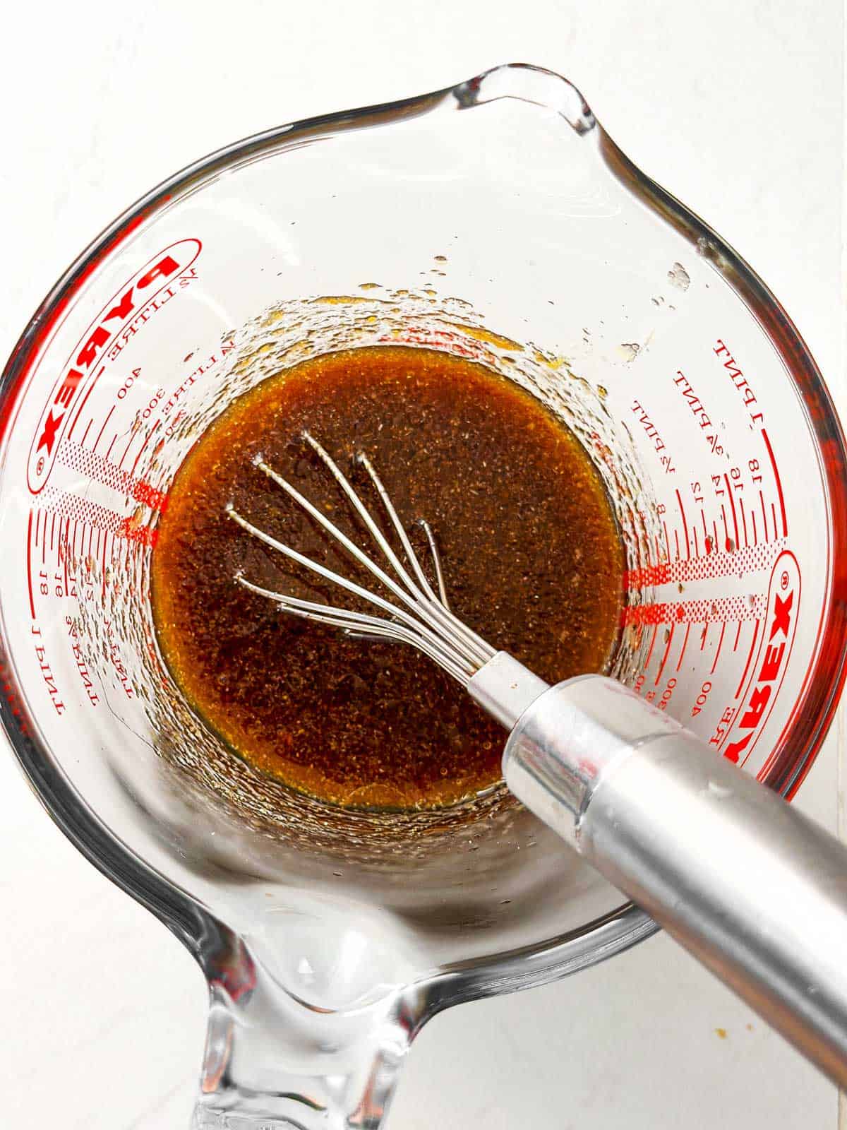 overhead view of whisked chicken thigh marinade in glass measuring jug