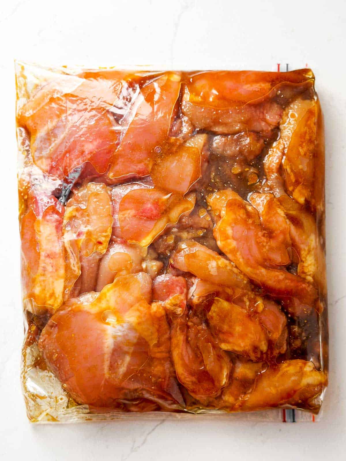 overhead view of zip-top bag filled with raw chicken thighs and marinade