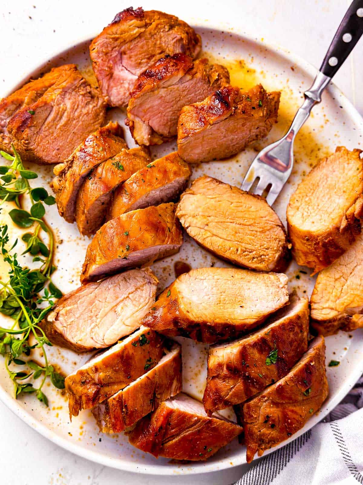 overhead view of sliced pork tenderloin on white plate with fork