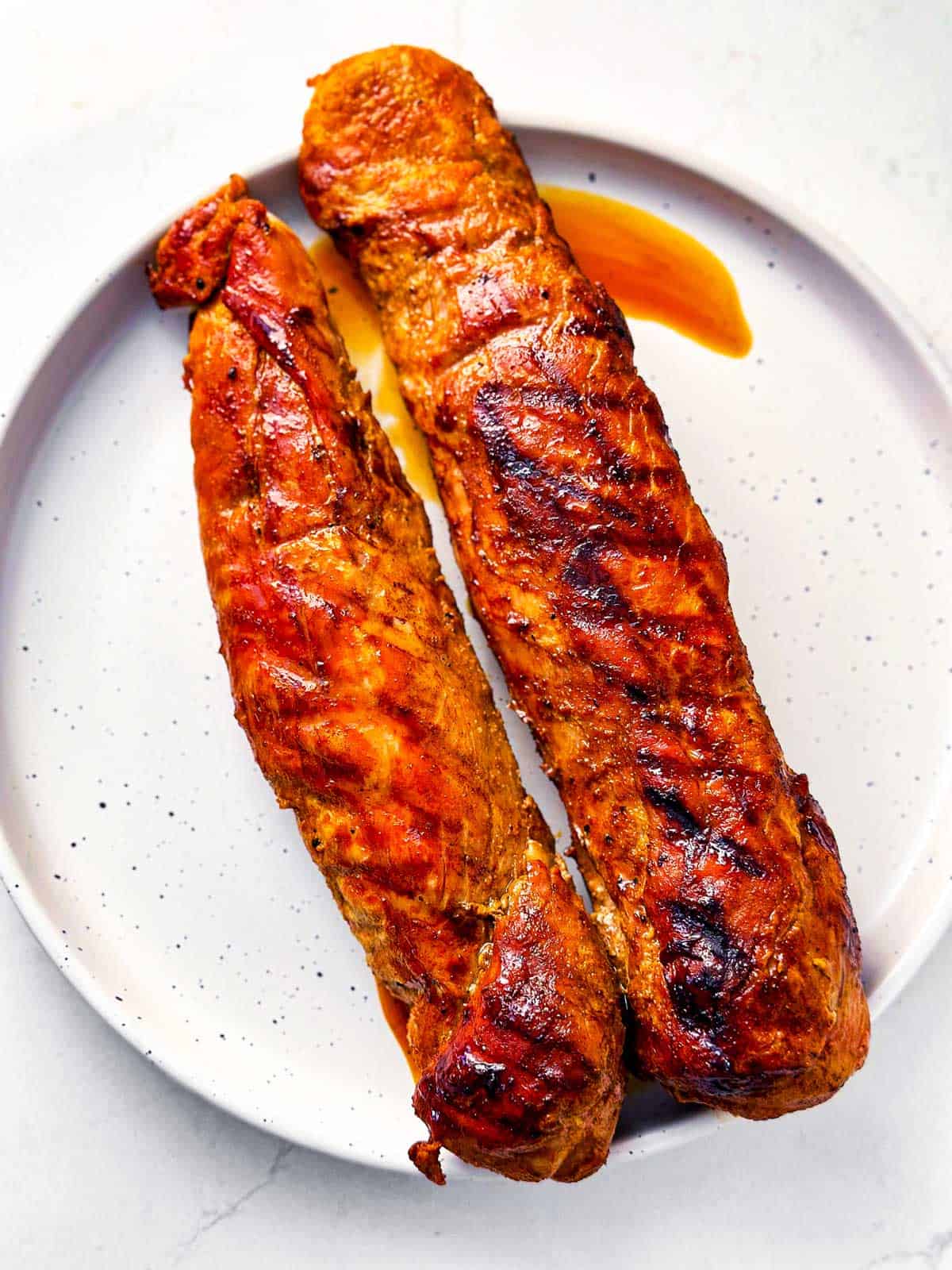 overhead view of cooked pork tenderloin on white plate