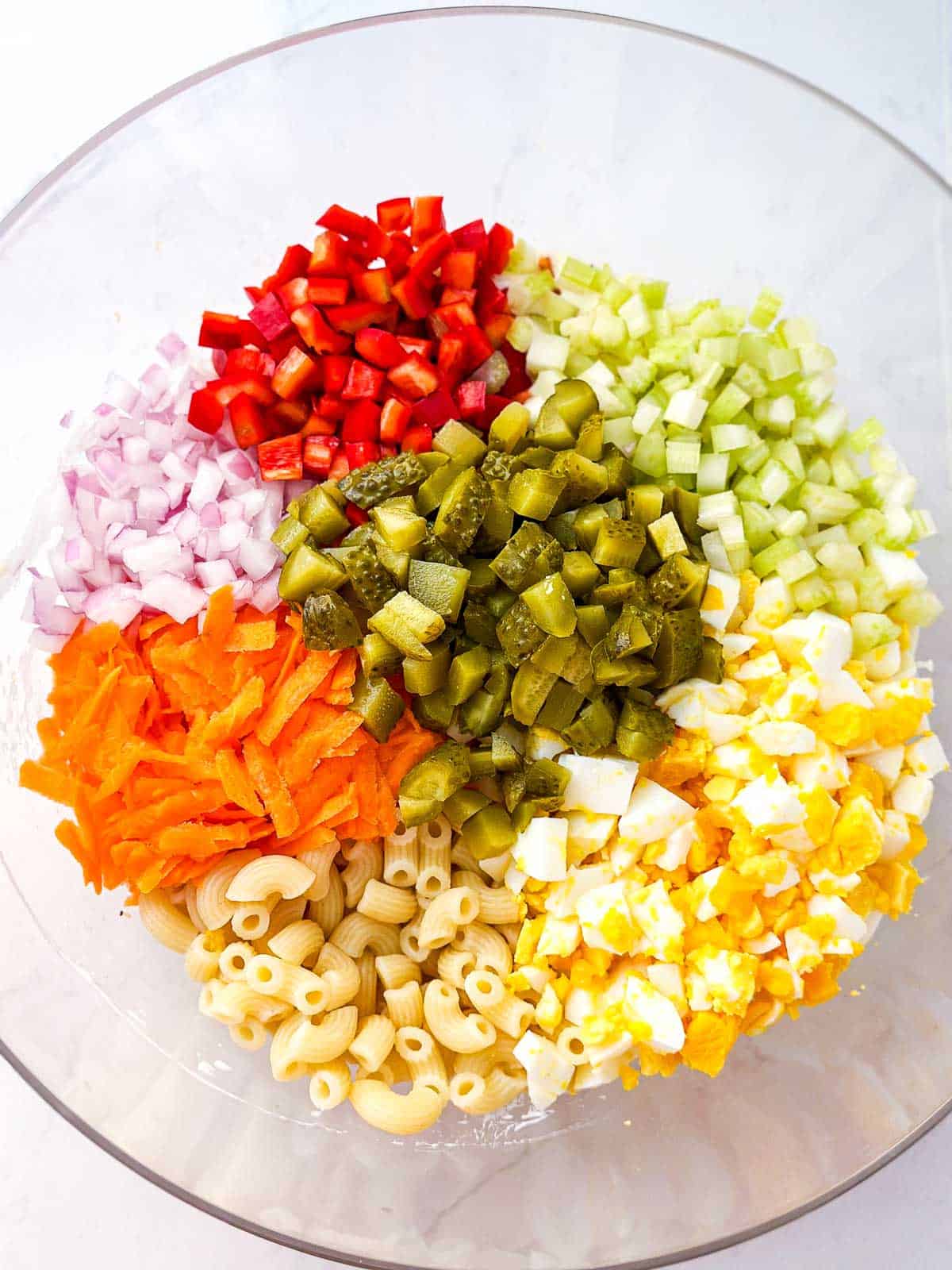 overhead view of macaroni salad ingredients in glass bowl
