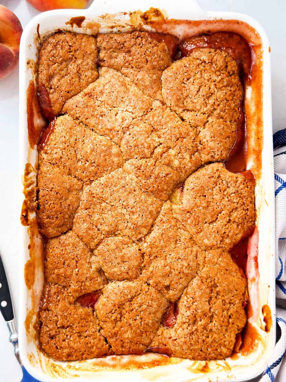overhead view of baked peach cobbler in white casserole dish