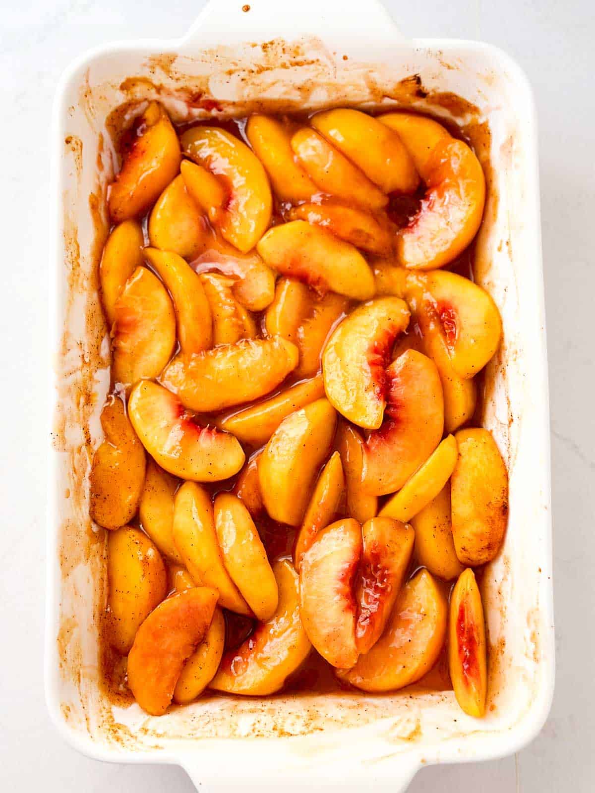 overhead view of cooked peach slices in white casserole dish