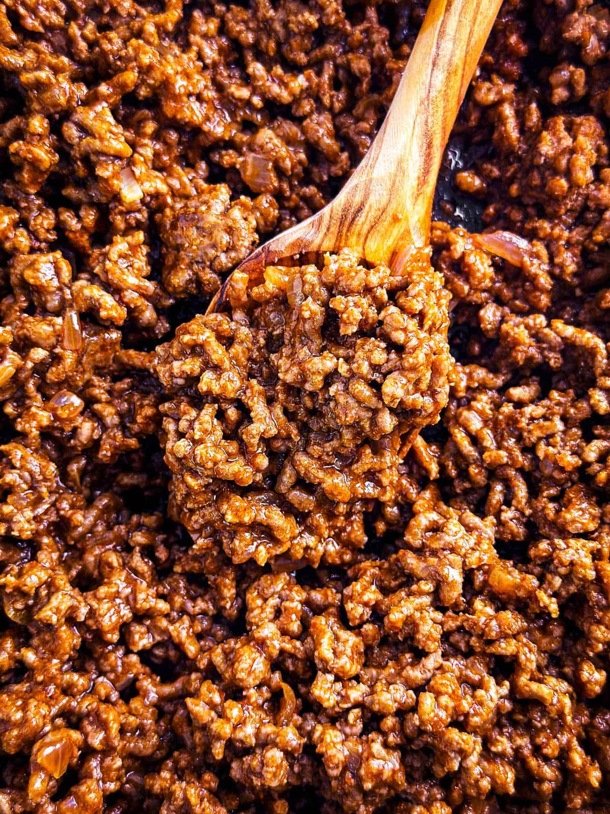 overhead close up view of taco meat with wooden spoon stuck in