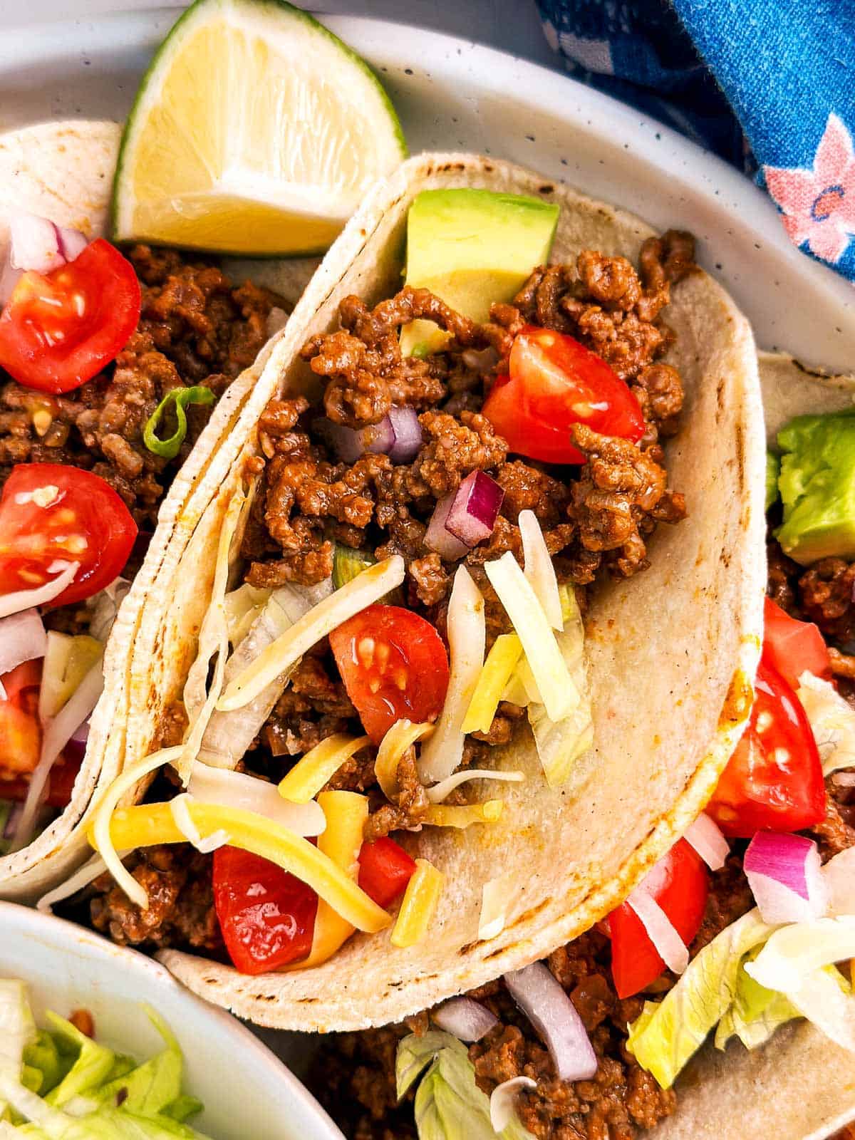 overhead close up view of ground beef taco on white plate with toppings