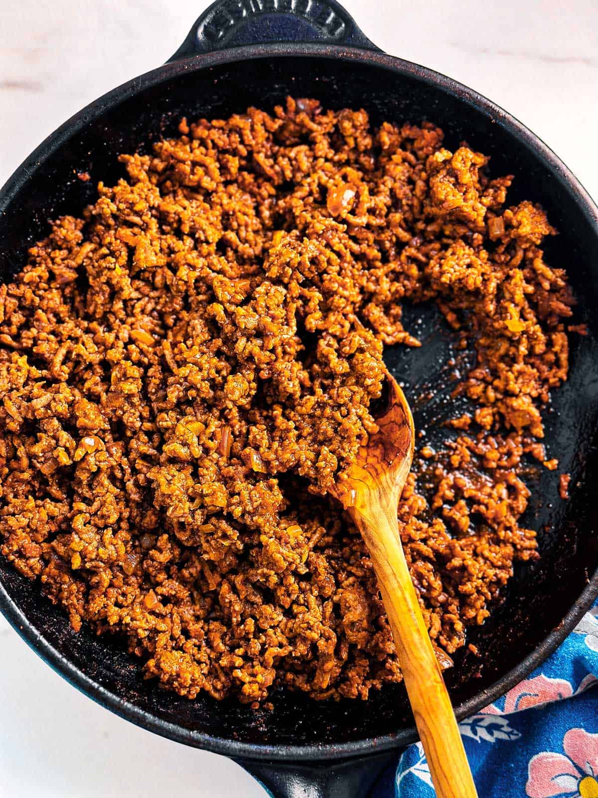 overhead view of taco meat in black skillet with wooden spoon