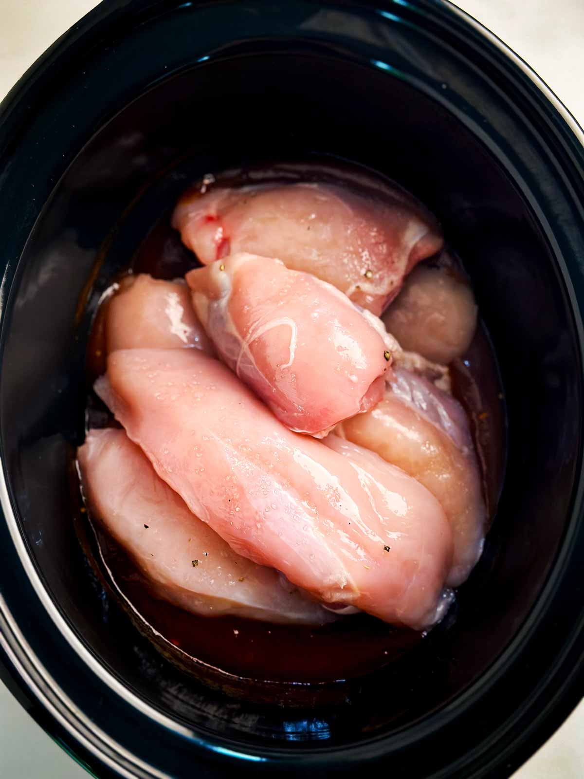 overhead view of raw chicken pieces in crock