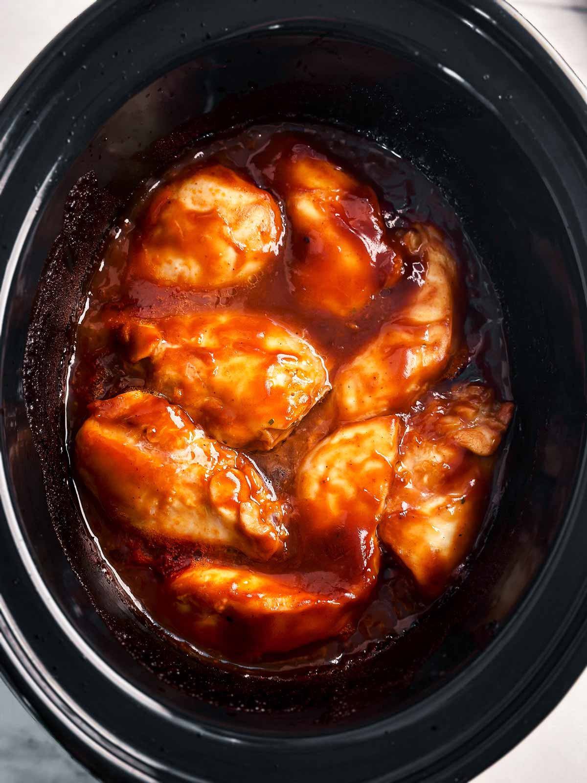 overhead view of cooked bbq chicken in slow cooker