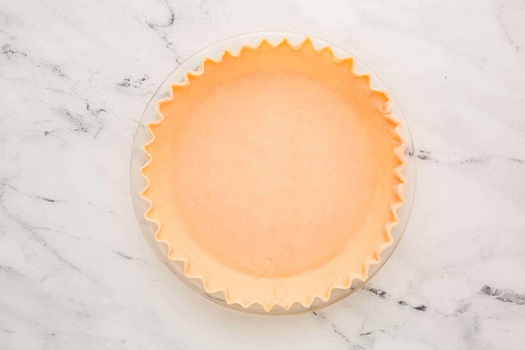 overhead view of pie crust in glass pie dish