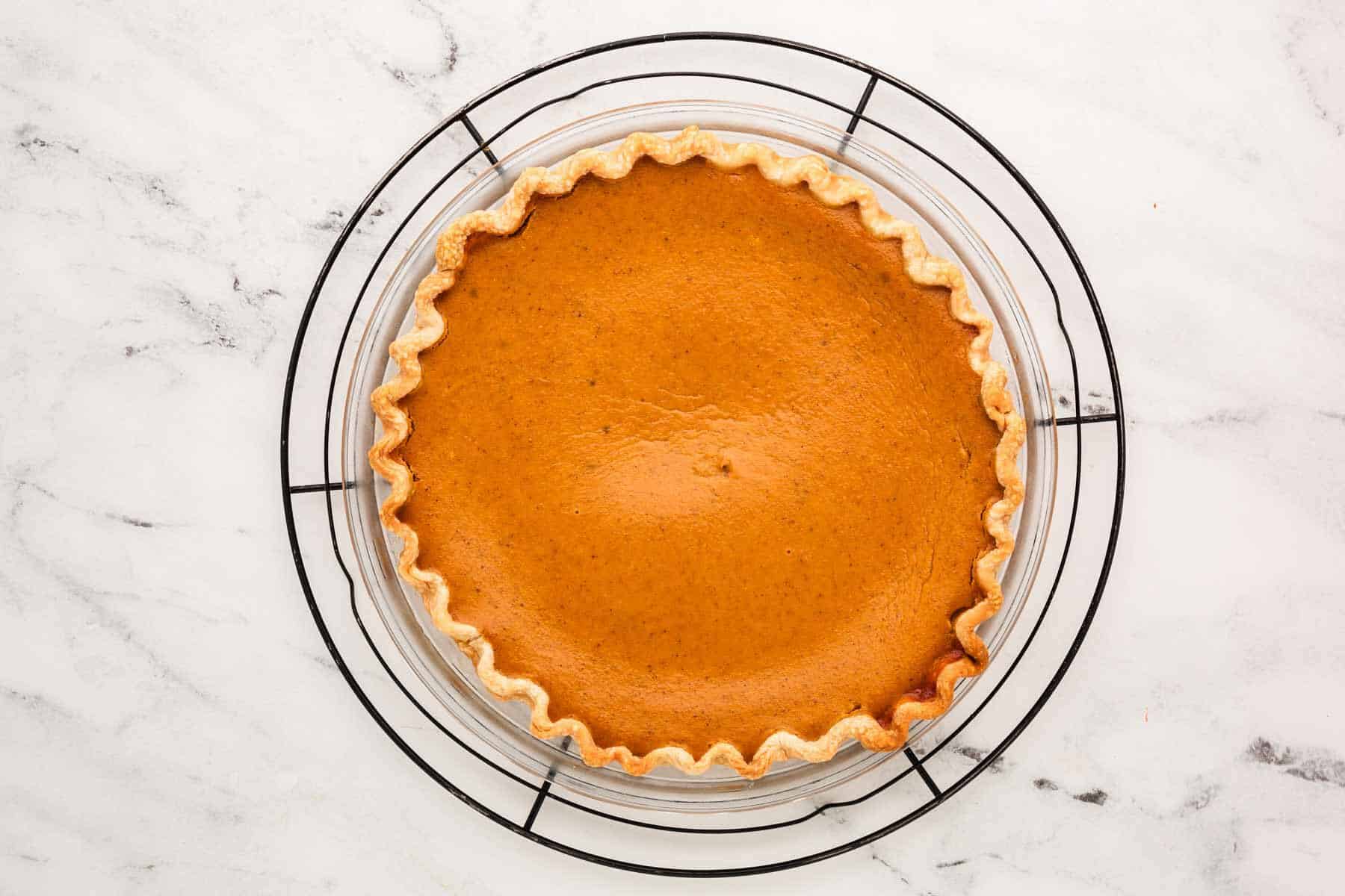 overhead view of baked pumpkin pie on black wire rack