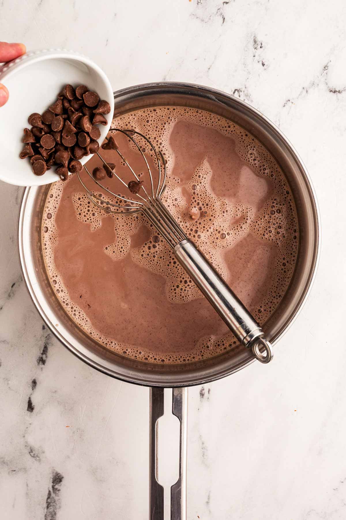 chocolate chips dropping into hot chocolate in saucepan