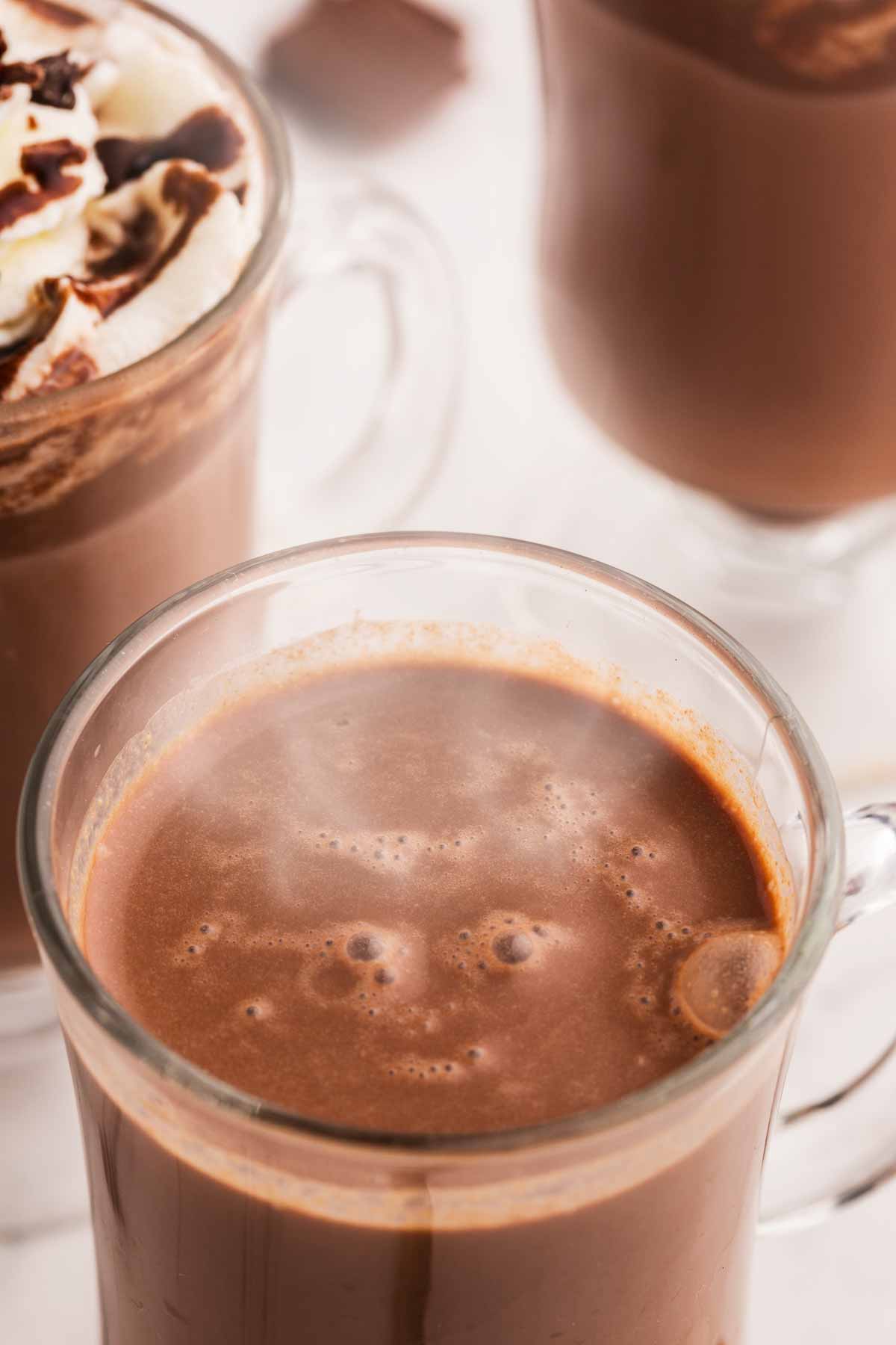 close up photo of steaming hot chocolate in glass mug