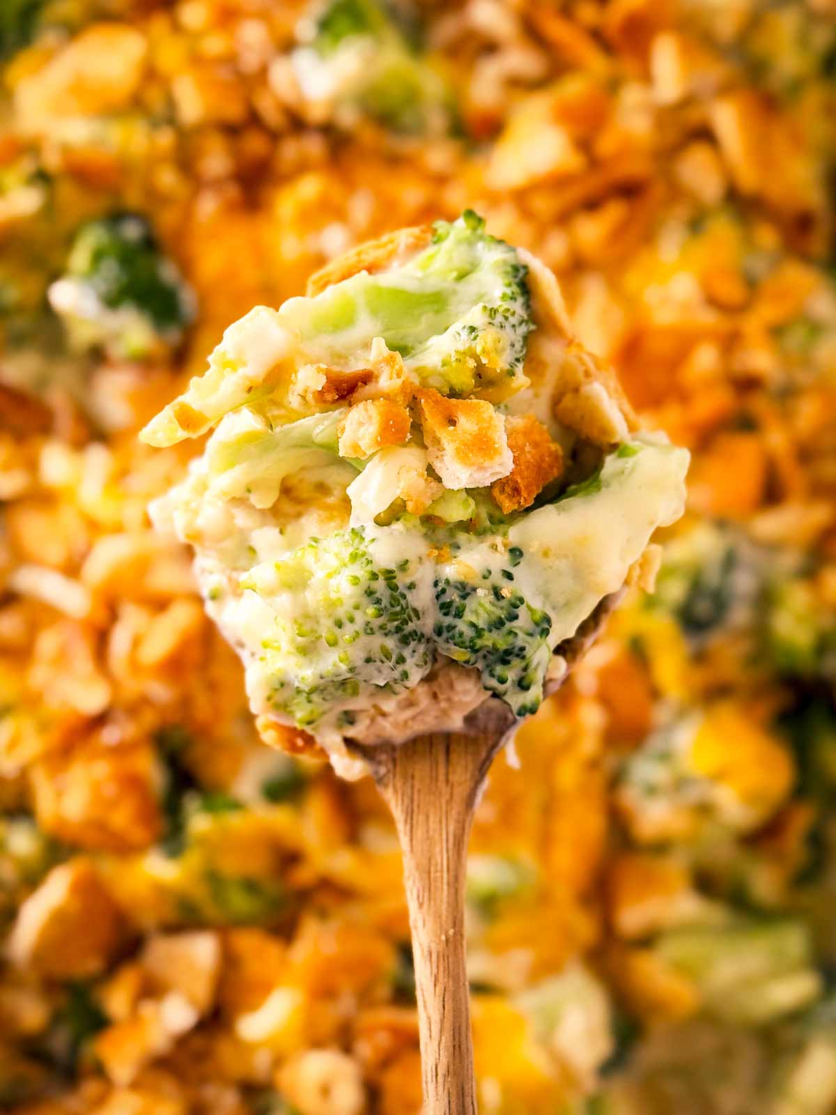 wooden spoon lifting broccoli casserole from dish