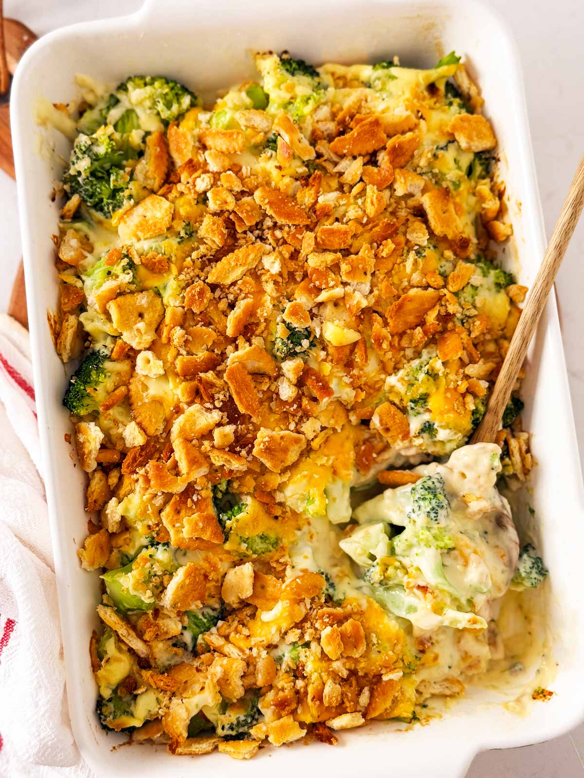 overhead view of broccoli cheese casserole with wooden spoon stuck in dish