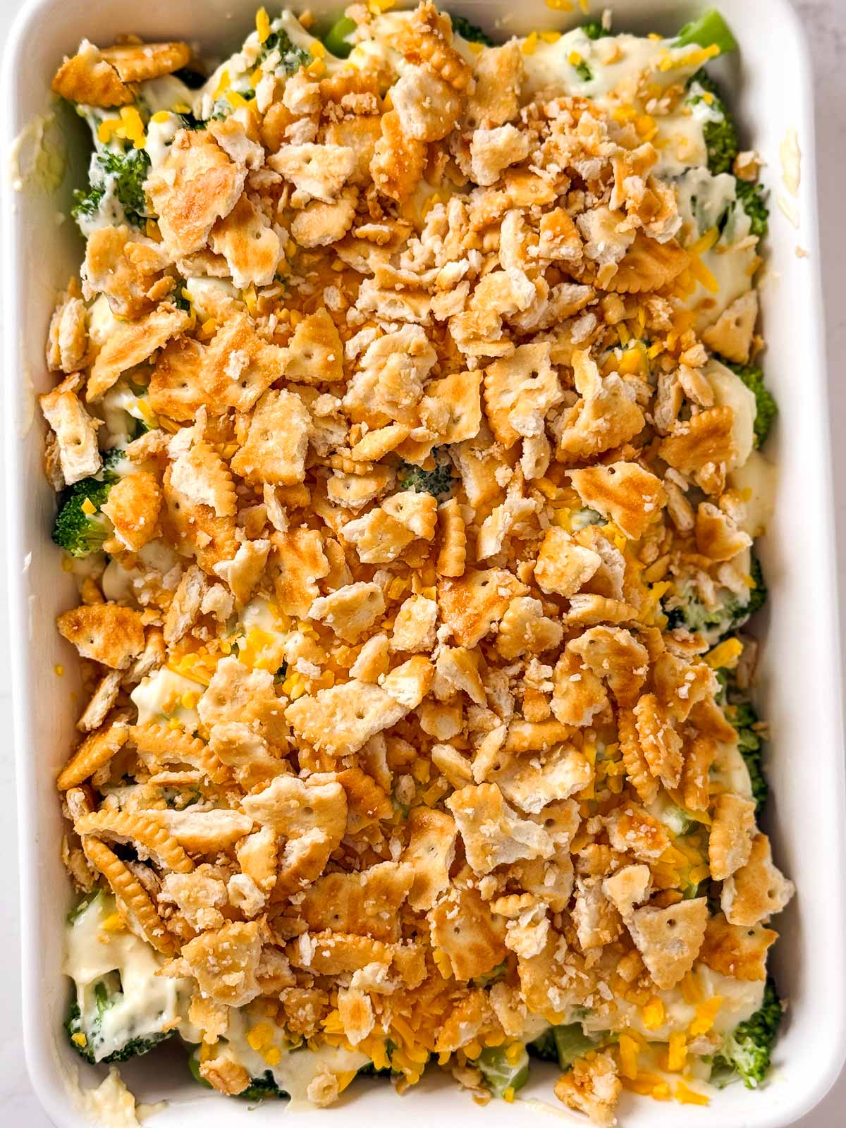 overhead view of unbaked broccoli cheese casserole with ritz crackers on top