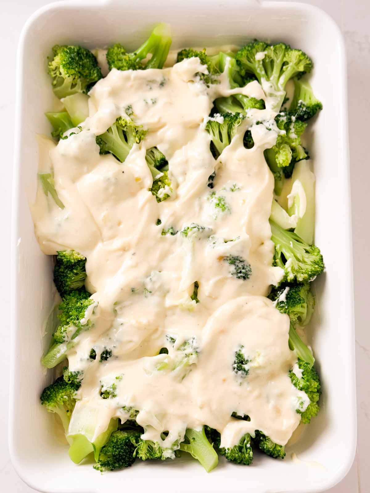 overhead view of broccoli covered with cheese sauce in casserole dish