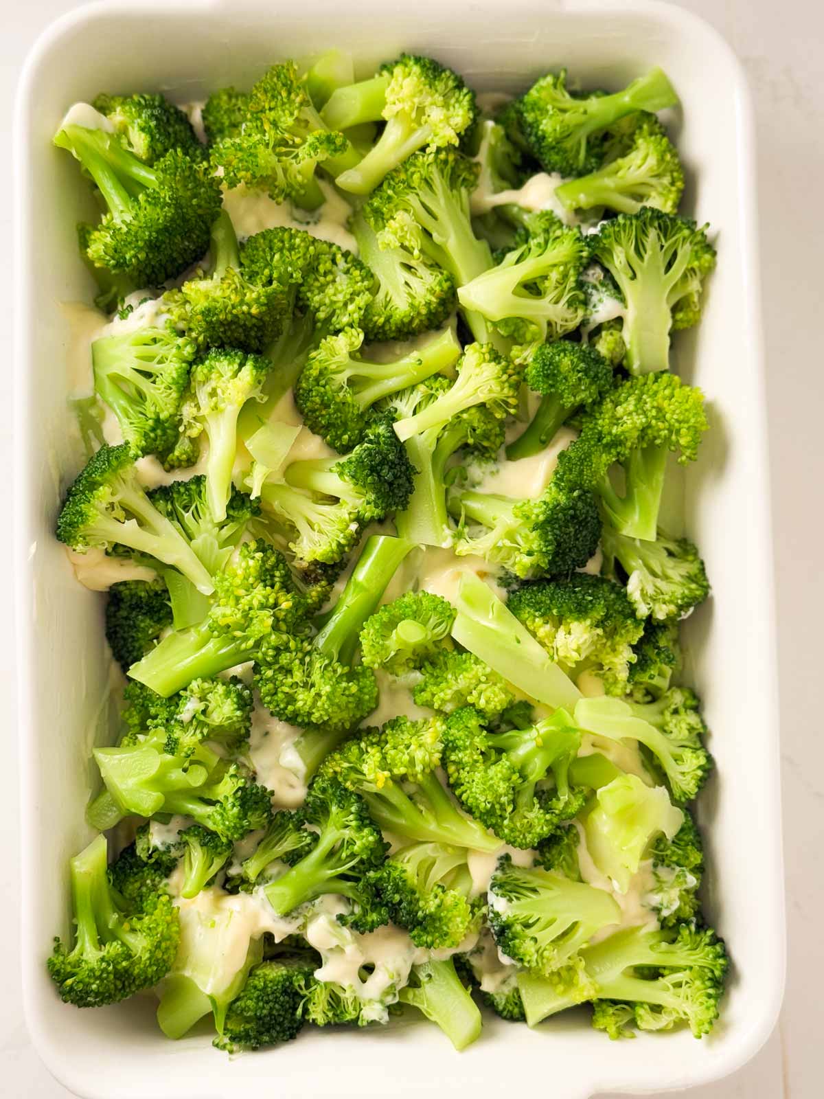 overhead view of broccoli on cheese sauce in casserole dish