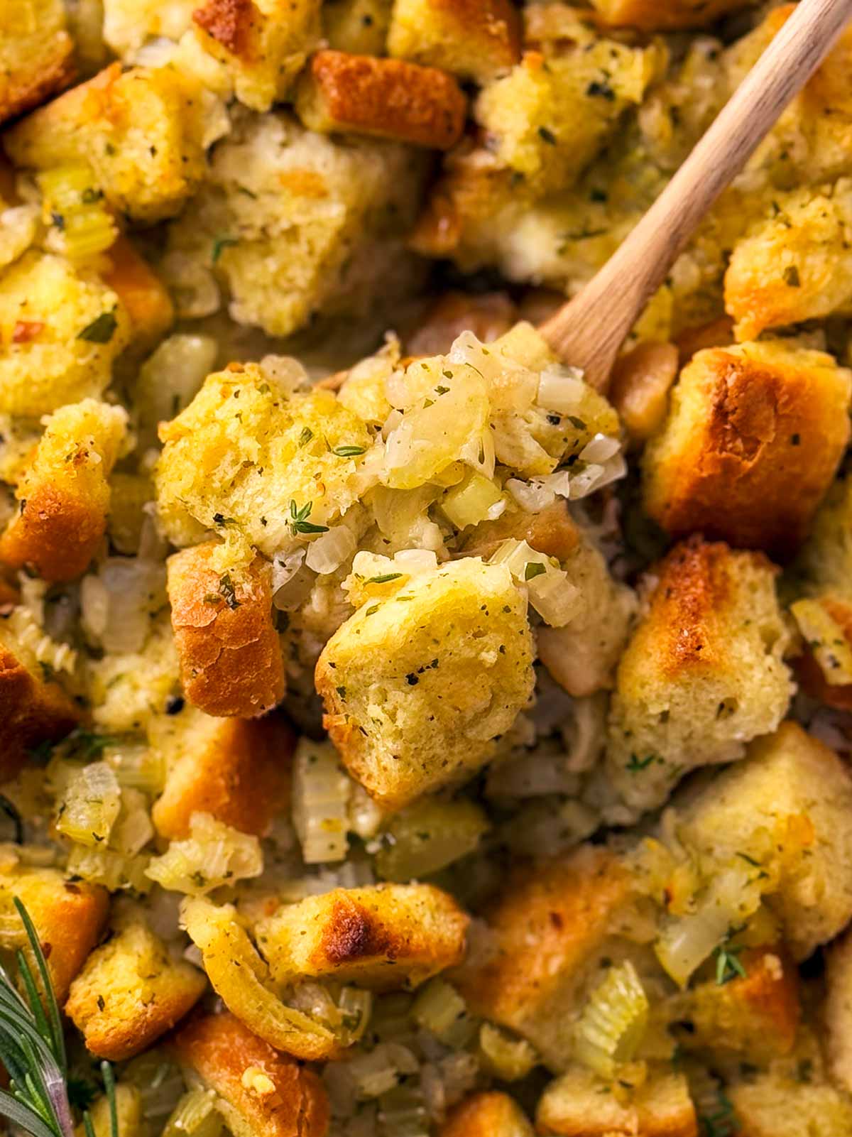 overhead close up photo of wooden spoon scooping stuffing from casserole